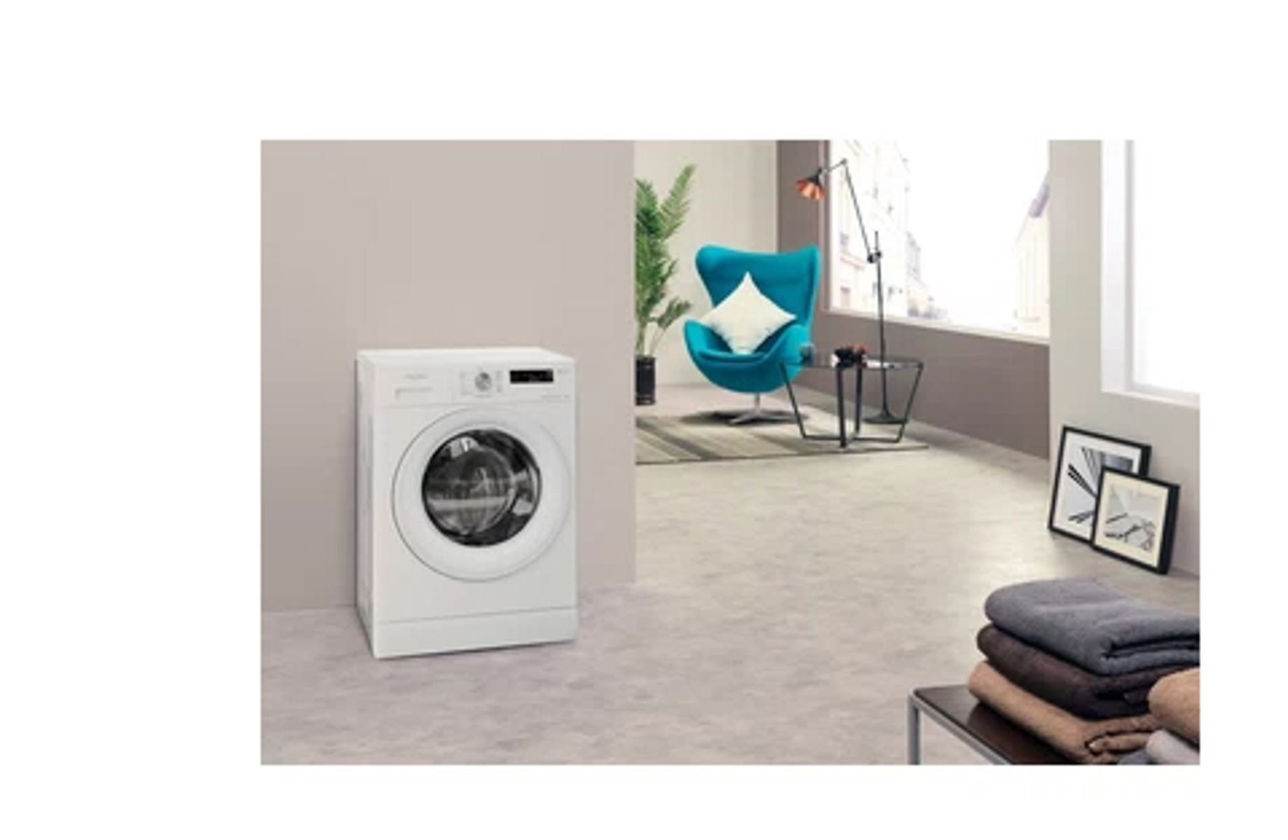 Una lavadora sola en una habitación, junto a una silla y algunas toallas.