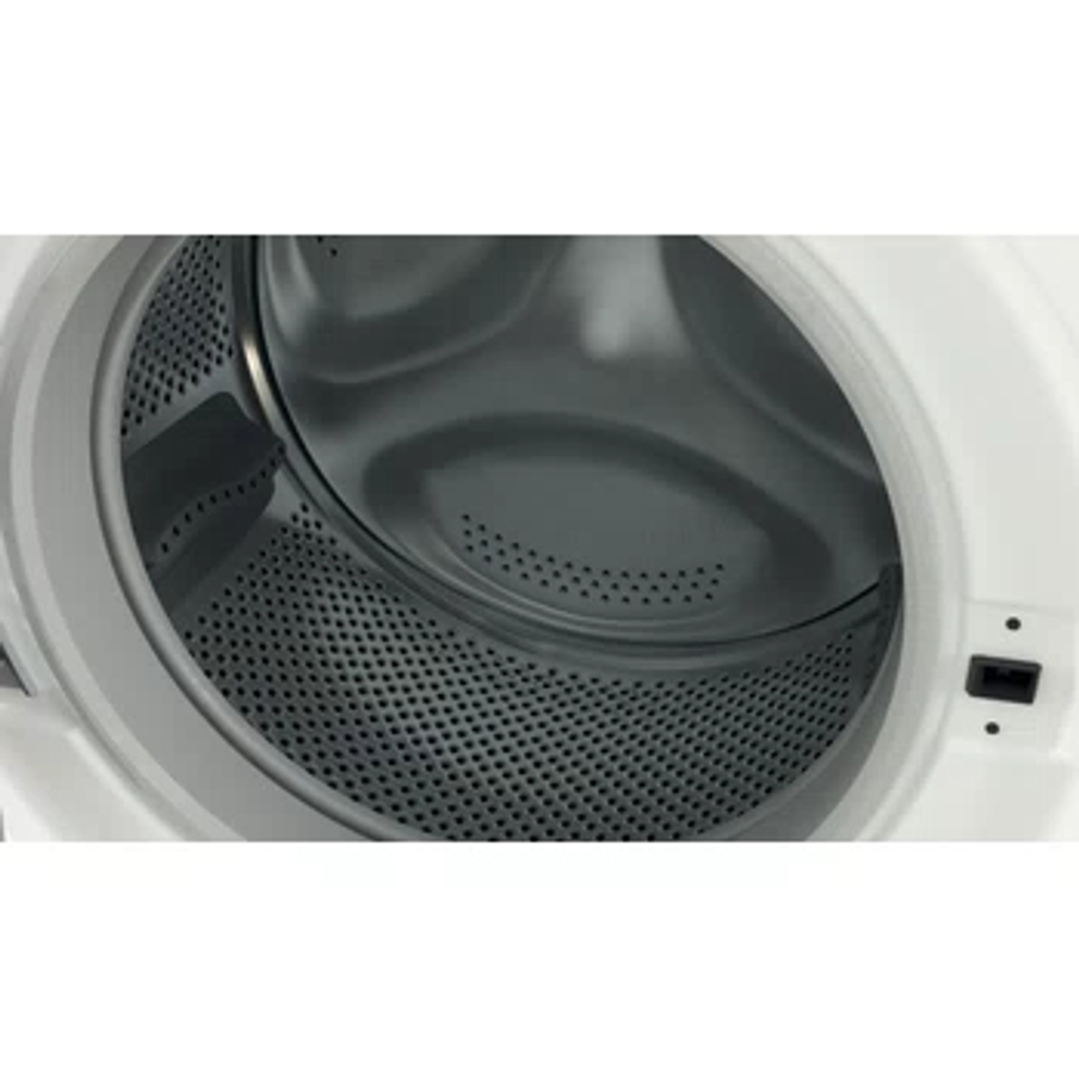Primer plano del interior del tambor de una lavadora blanca con perforaciones.