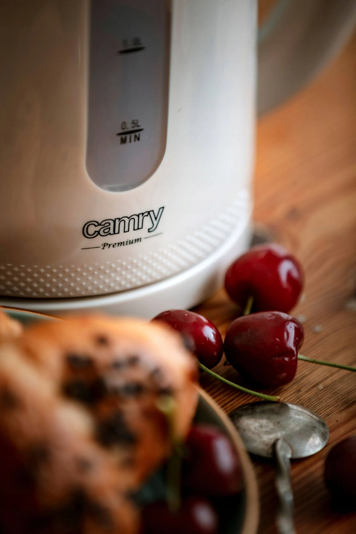 Biały czajnik elektryczny Camy z wiśniami i łyżką na pierwszym planie.