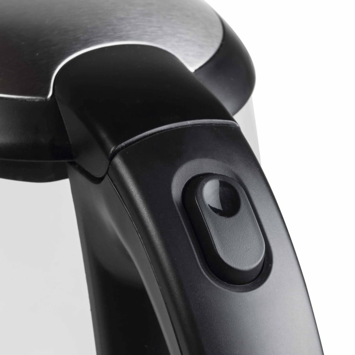 Zbliżenie czarnego przycisku zasilania na uchwycie białego czajnika.