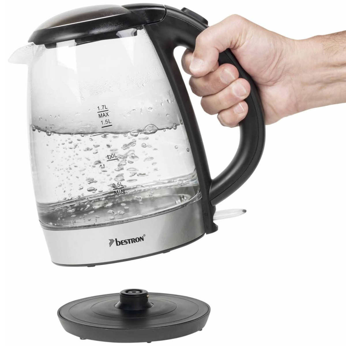 Dłoń trzymająca szklany czajnik elektryczny wypełniony wodą.