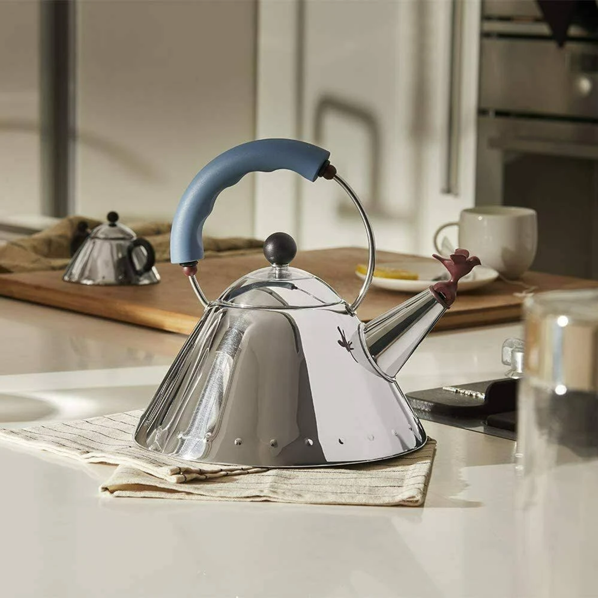 Teiera cromata su un piano cucina con manico blu.