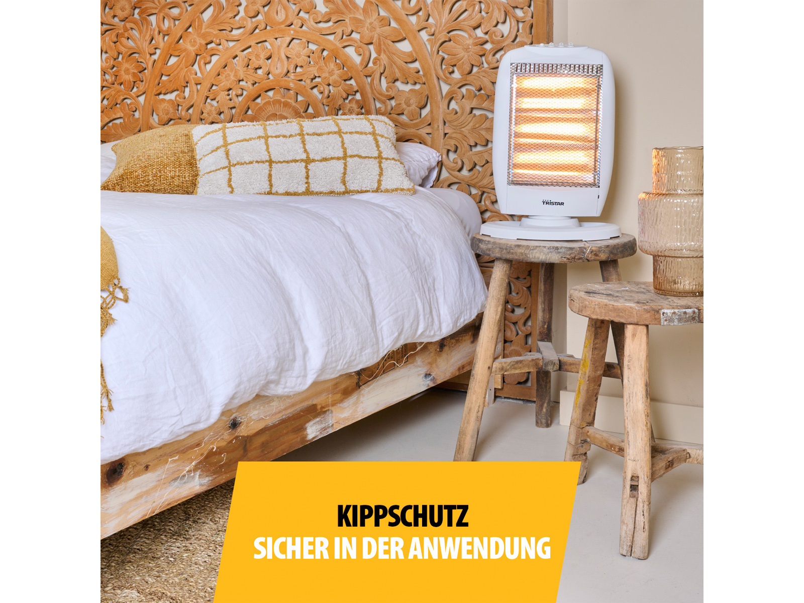 Un termoventilatore bianco su uno sgabello di legno accanto a un letto. Il termoventilatore è acceso.