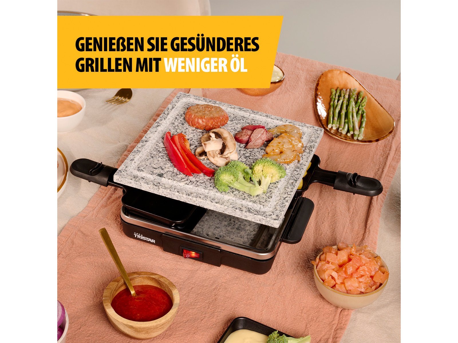 Ein Tischgrill mit Essen. Text oben sagt: 'Genießen Sie gesünderes Grillen mit weniger Öl'.
