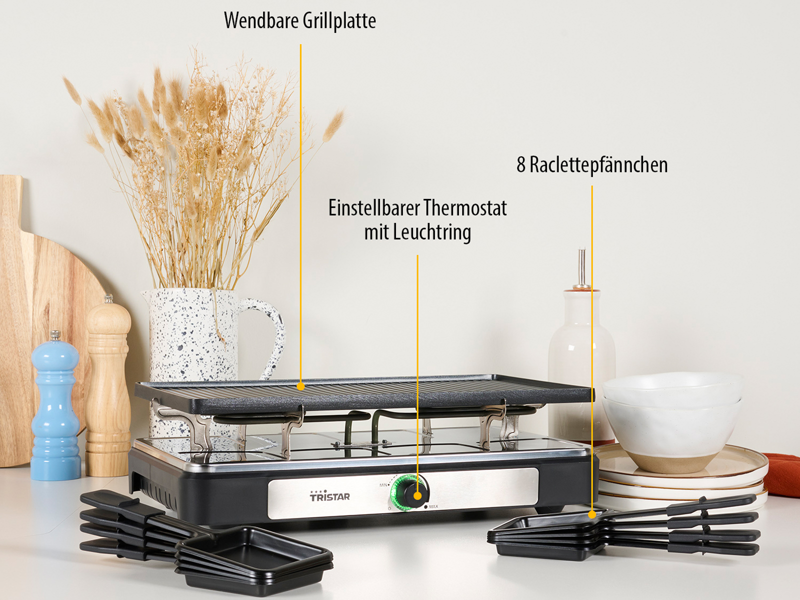 Griglia per raclette con piastra, termostato e padelle. Accessori e decorazioni visibili.