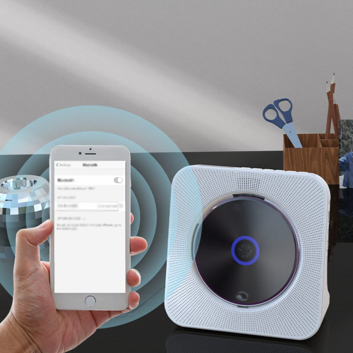 Weißer CD-Player mit blauem Licht. Telefon zeigt Bluetooth-Verbindung. Holztisch, Hintergrund.