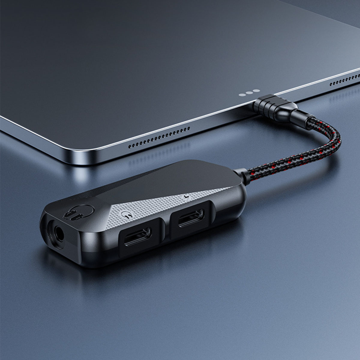 Schwarzer Adapter, an ein Tablet angeschlossen. Es hat mehrere Anschlüsse und ein rot/schwarzes Kabel.