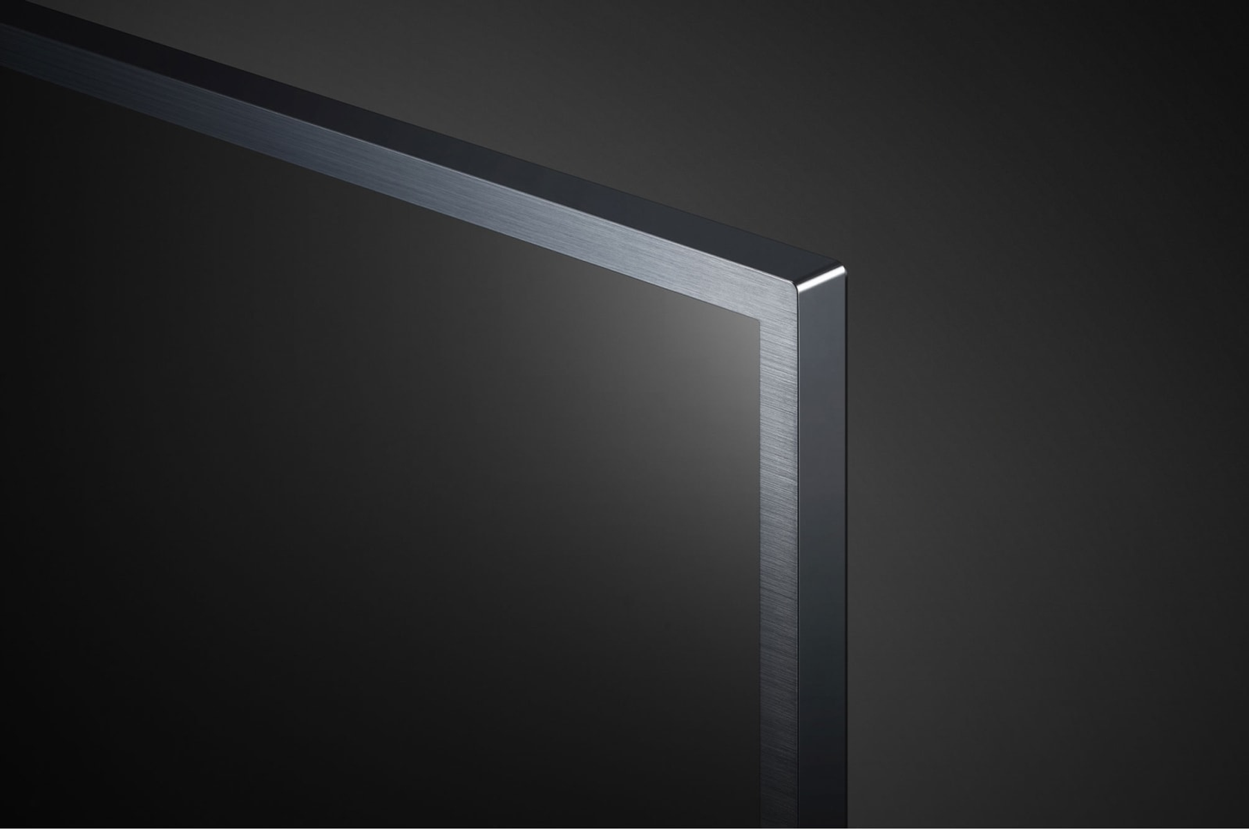 Zbliżenie rogu telewizora z czarną ramą na ciemnym tle.