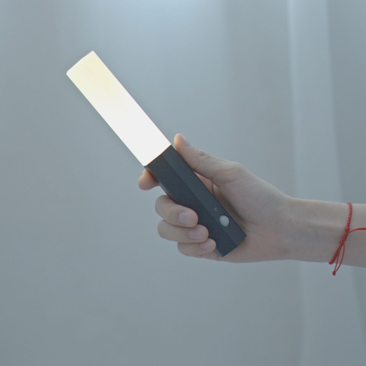 Eine Hand hält eine schwarz-weiße Taschenlampe mit hellem Licht.