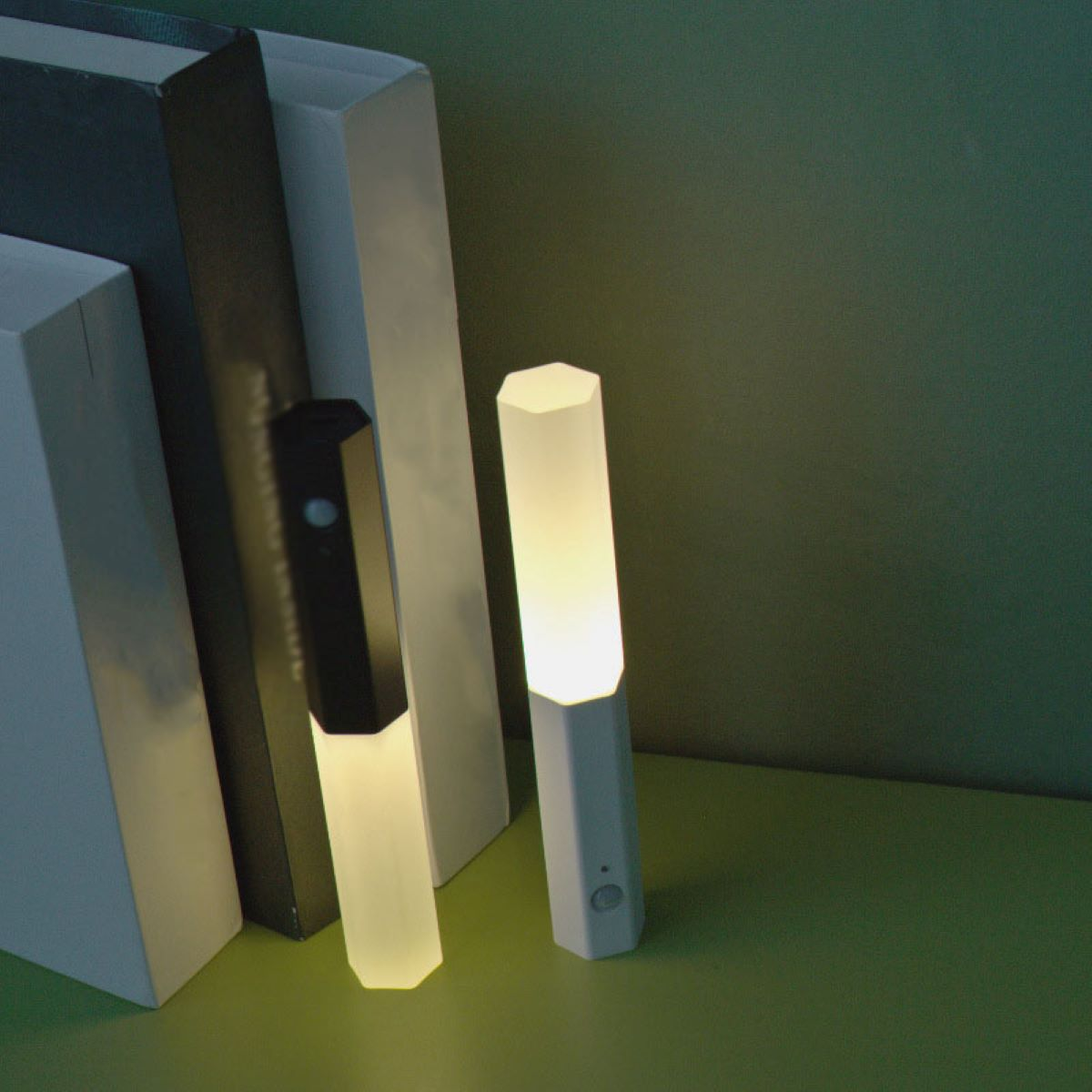 Zwei moderne, sechseckige, weiße und schwarze Lichter mit sanftem Glanz, neben Büchern.
