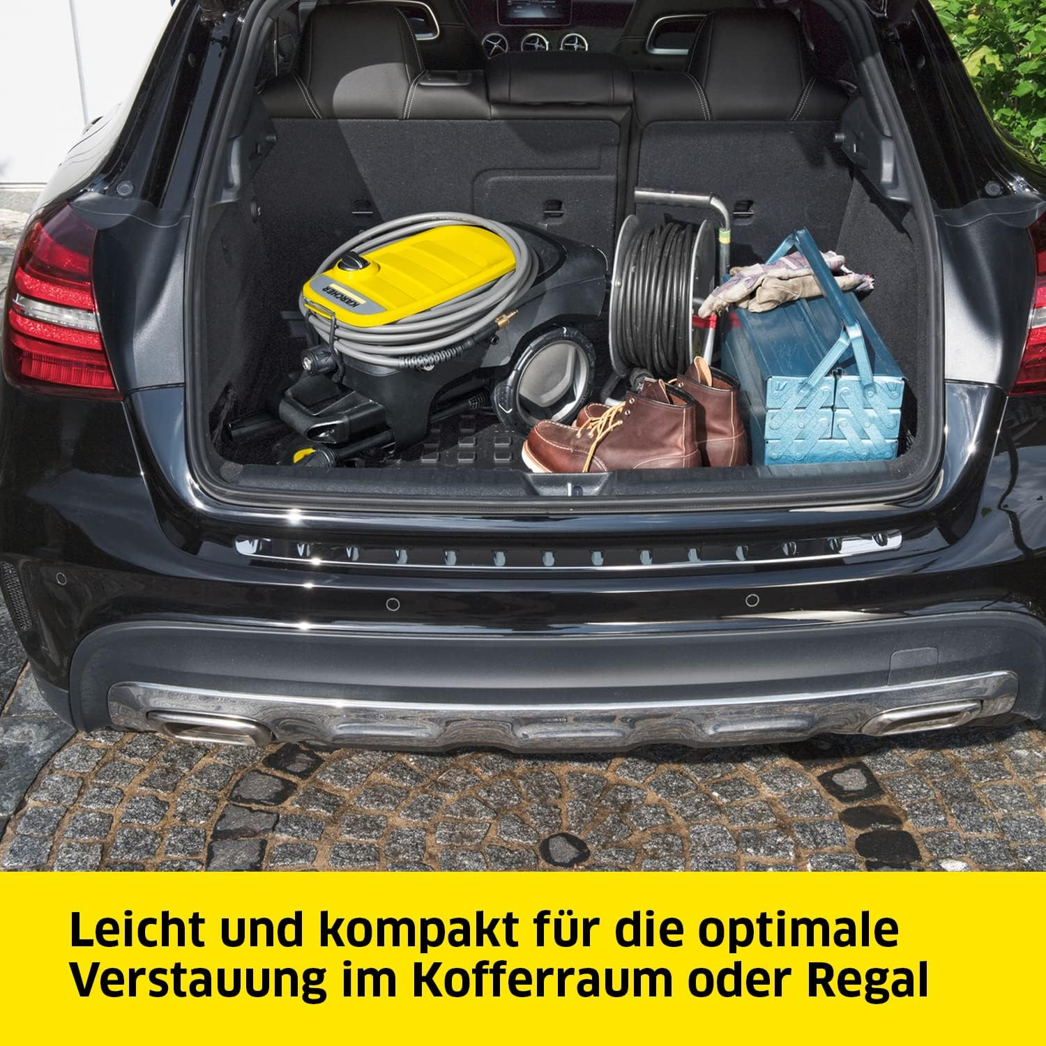 Bagagliaio dell'auto aperto, contenente un'idropulitrice, scarpe e una cassetta degli attrezzi.