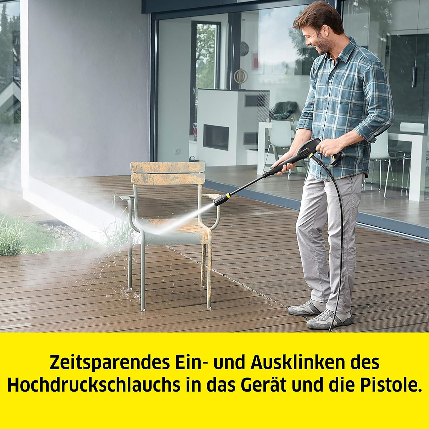 Ein Mann reinigt einen Holzstuhl mit einem Hochdruckreiniger auf einer Holzterrasse.