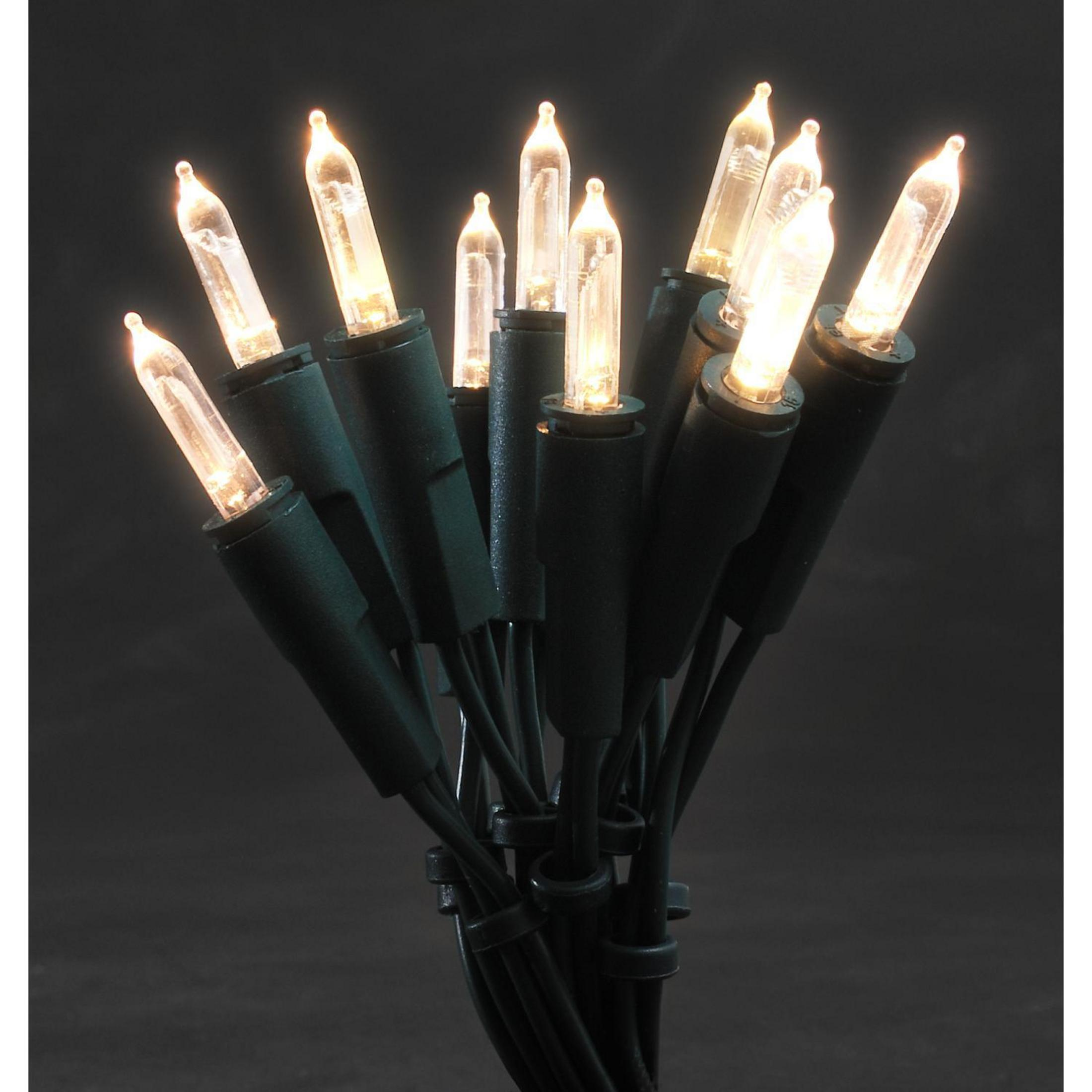 Nahaufnahme von Weihnachtslichtern; klare Glühbirnen mit grünen Drähten auf dunklem Hintergrund, Lichter sind an.