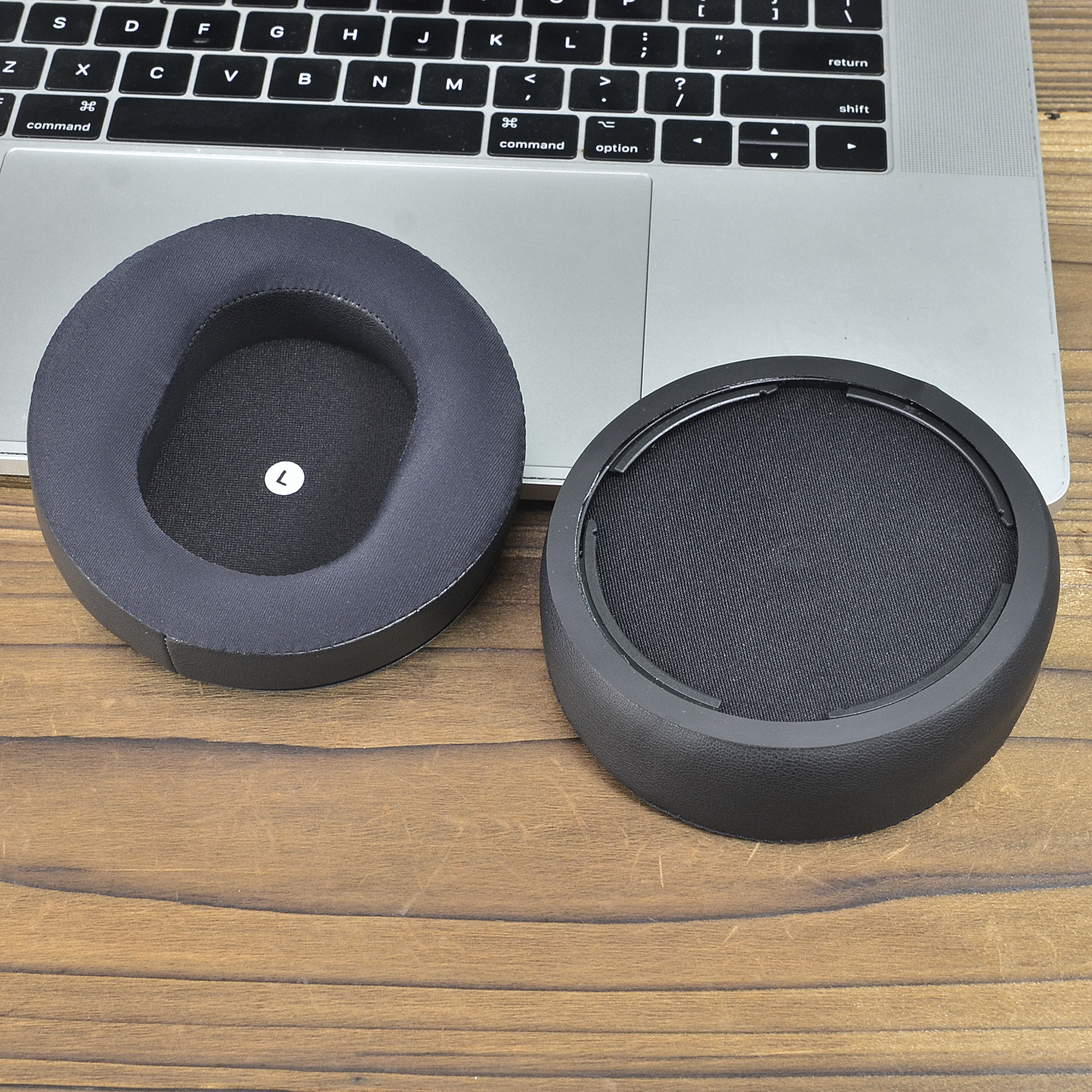 Poduszki na uszy do słuchawek, odłączone. Jeden pokazuje 'L', a drugi wewnętrzną siatkę.