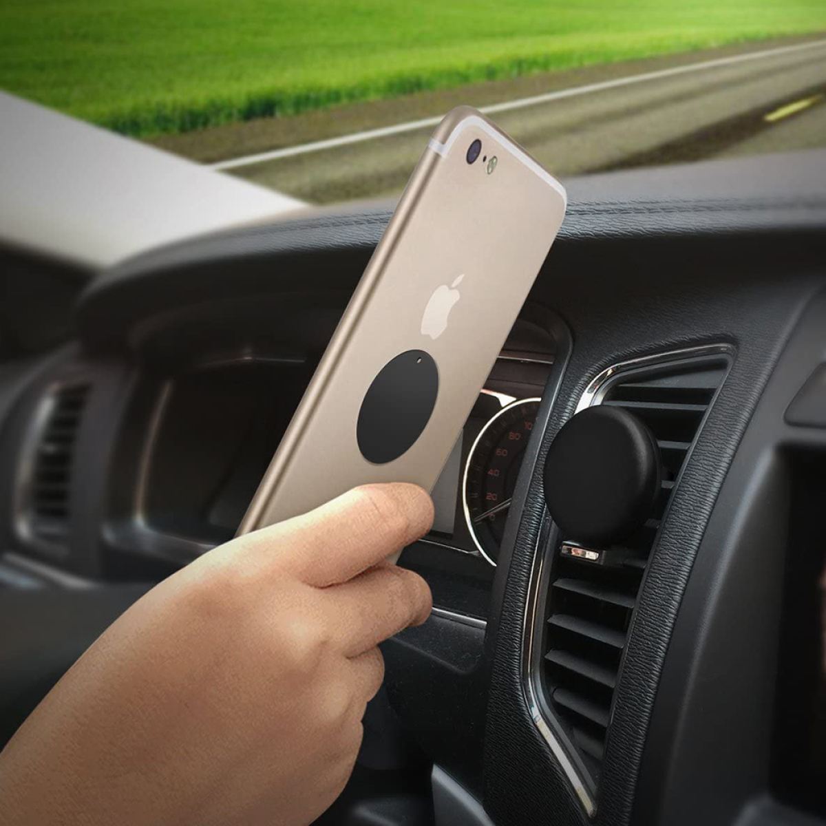 Eine Hand, die ein goldenes iPhone in einem Auto hält, das mit einem schwarzen Magneten am Armaturenbrett befestigt ist.