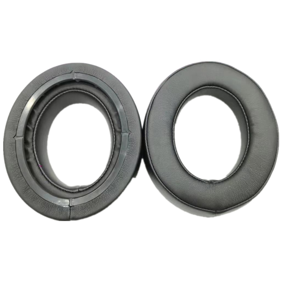 Dwie czarne, okrągłe nauszniki z centralnym otworem. Jedna nausznica ma szary pierścień.