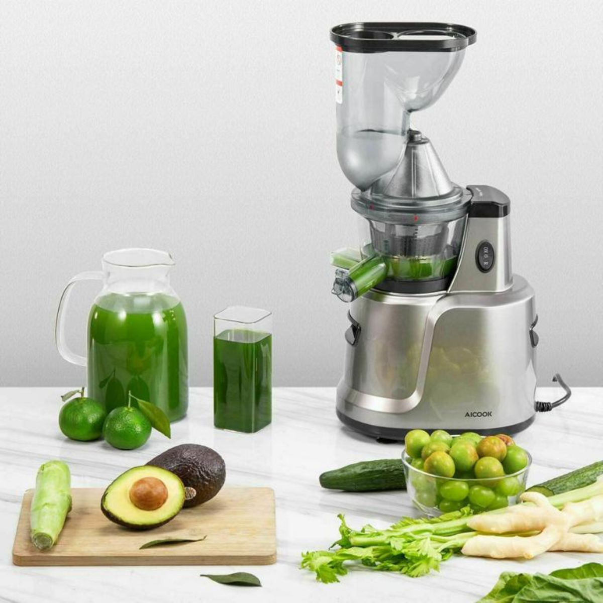 Entsafter mit Früchten, Gemüse und Saft. Der Entsafter ist silber.