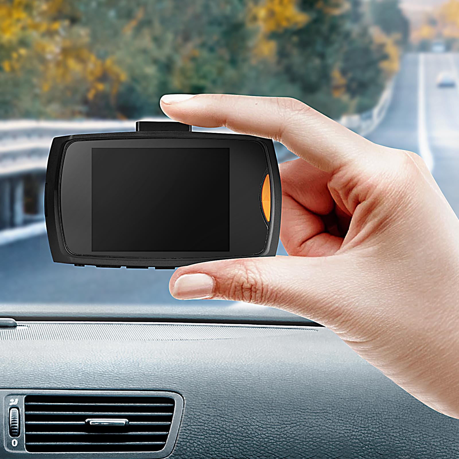 Hand hält Dashcam vor einem unscharfen Straßenhintergrund.