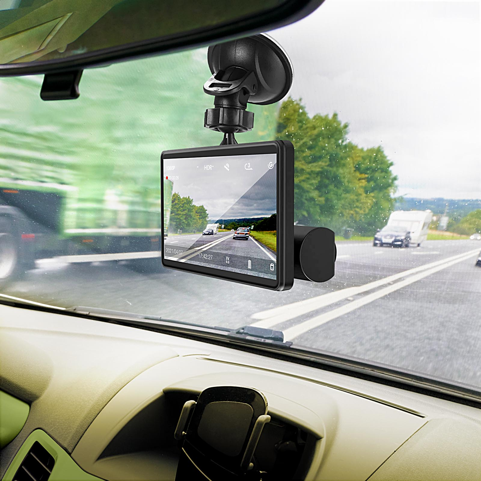 Armaturenbrett mit Dashcam, die die Straße zeigt. Draußen fahren Autos und ein Wohnwagen.