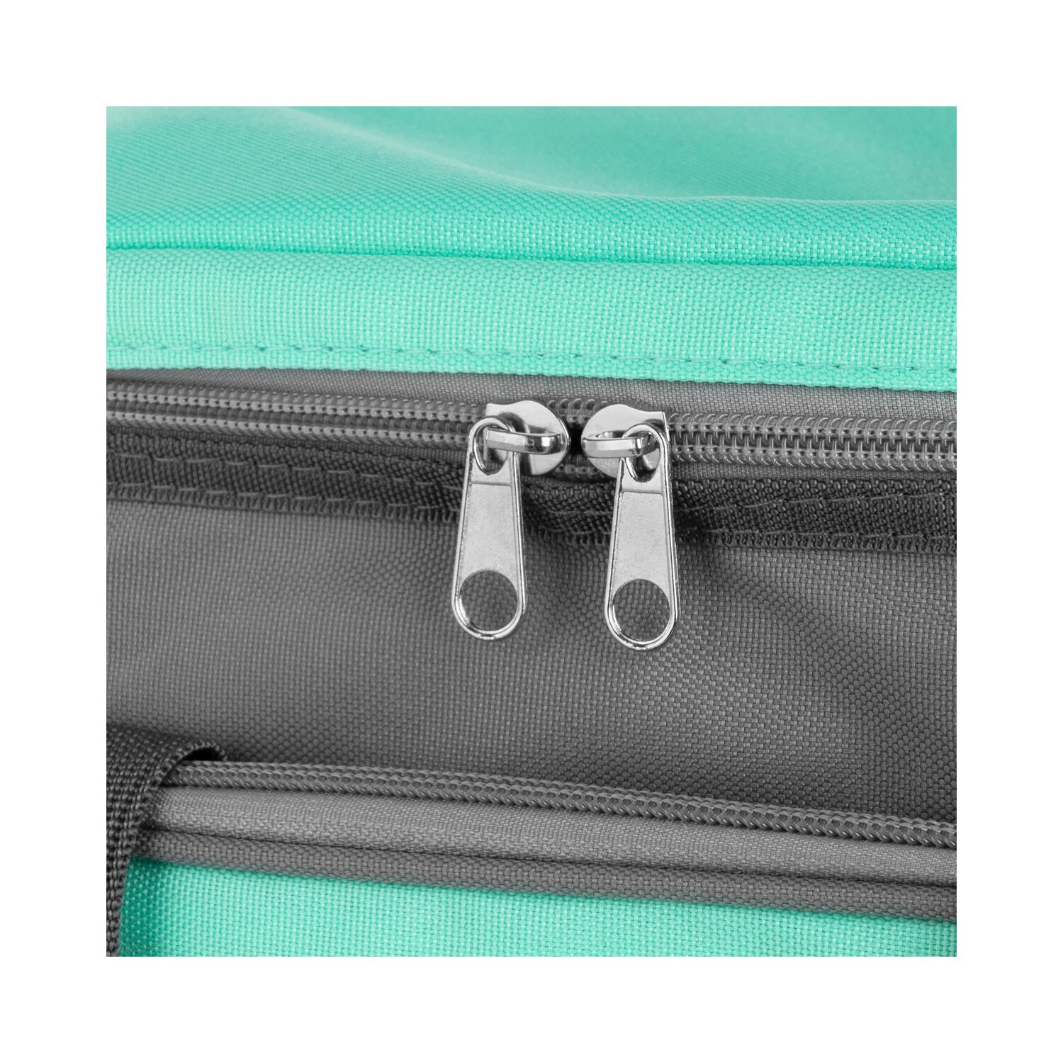 Nahaufnahme einer türkis-grauen Tasche mit zwei silbernen Reißverschlüssen auf weißem Hintergrund.