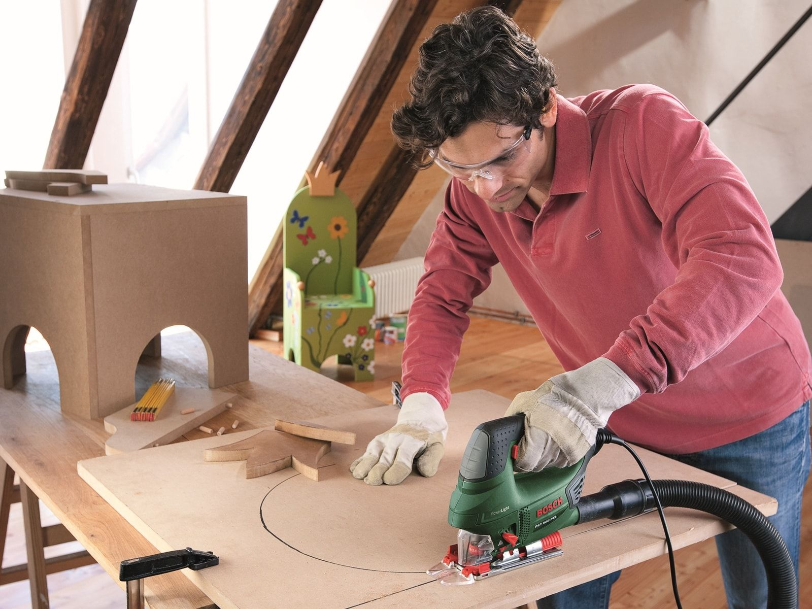 Mężczyzna tnący drewno zieloną wyrzynarką, drewniany stół.