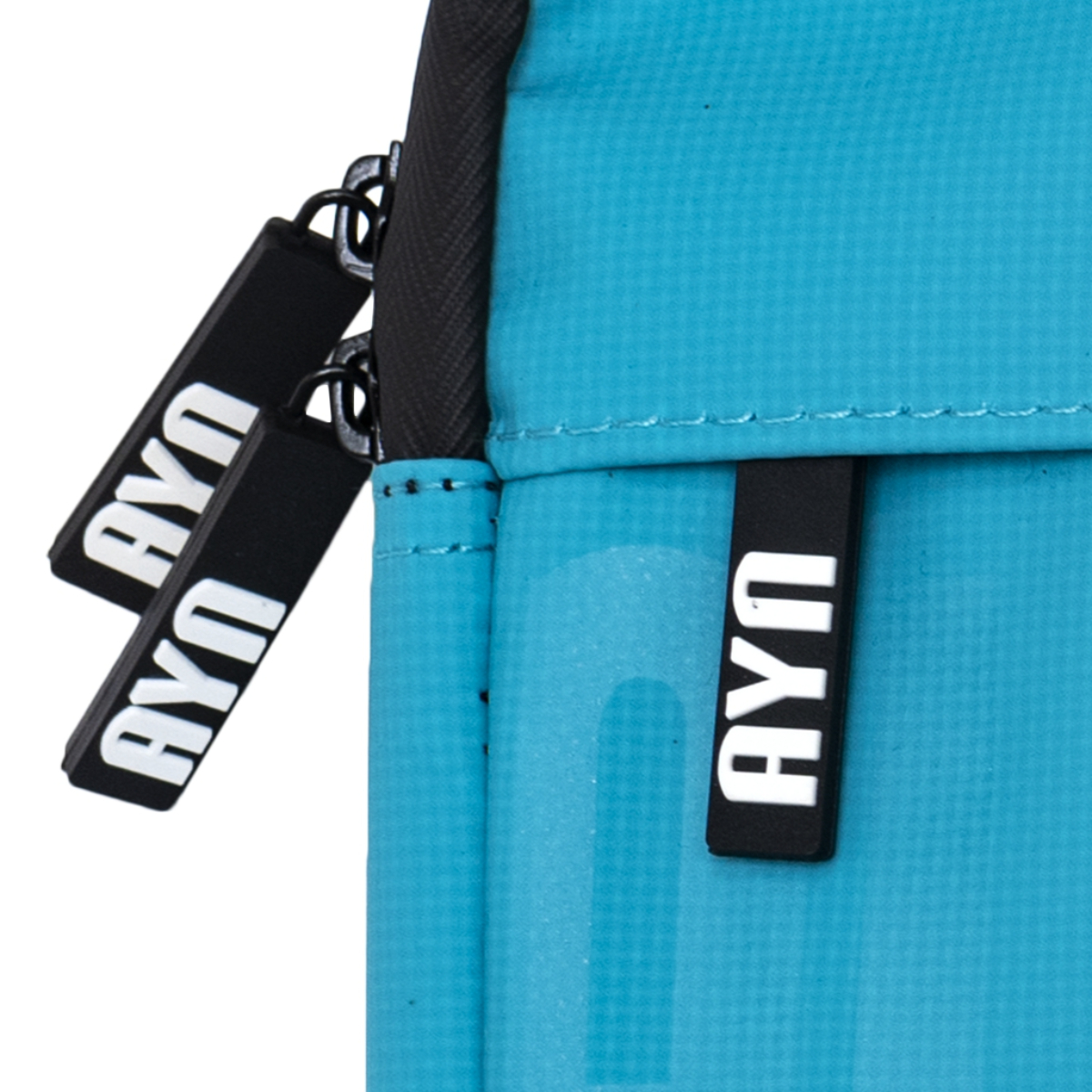 Un primo piano di una borsa blu con cerniere nere. La borsa ha etichette AYU bianche.