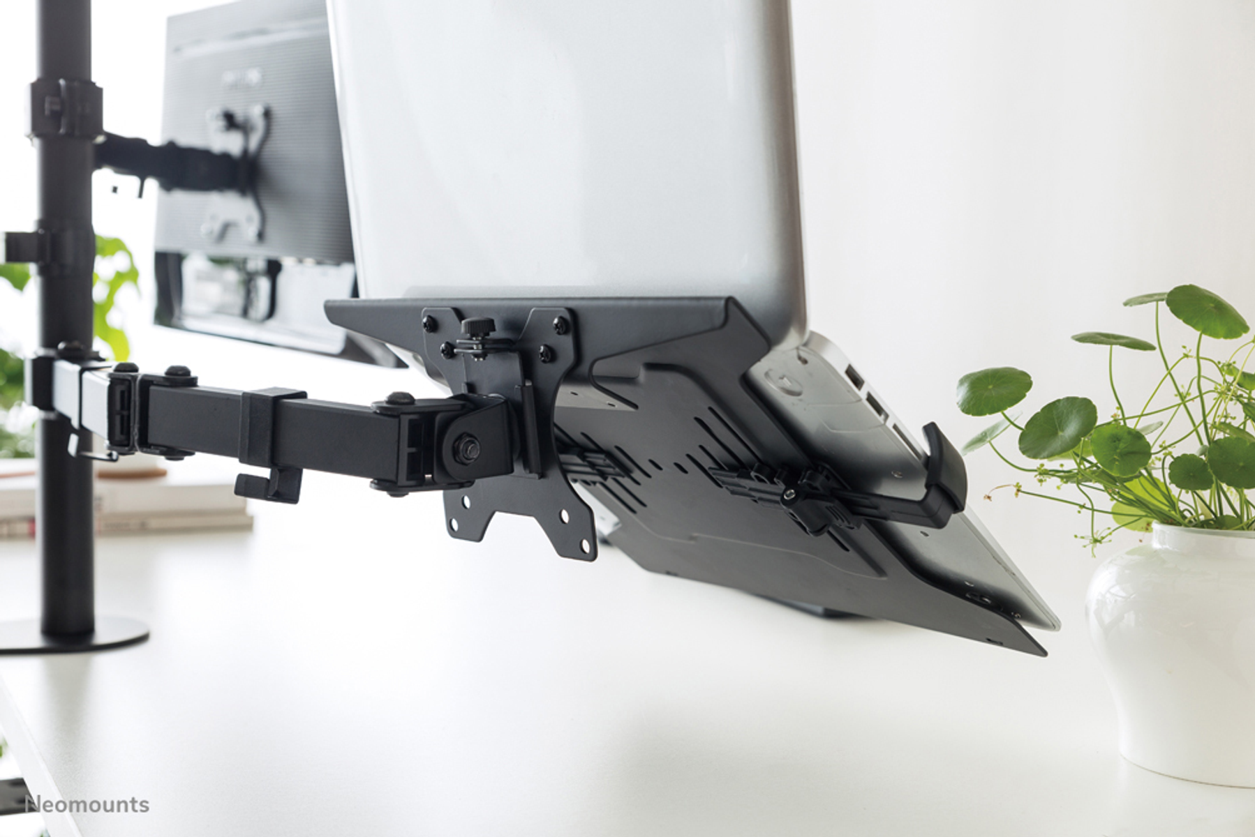 A black monitor arm holds two screens above a white desk.