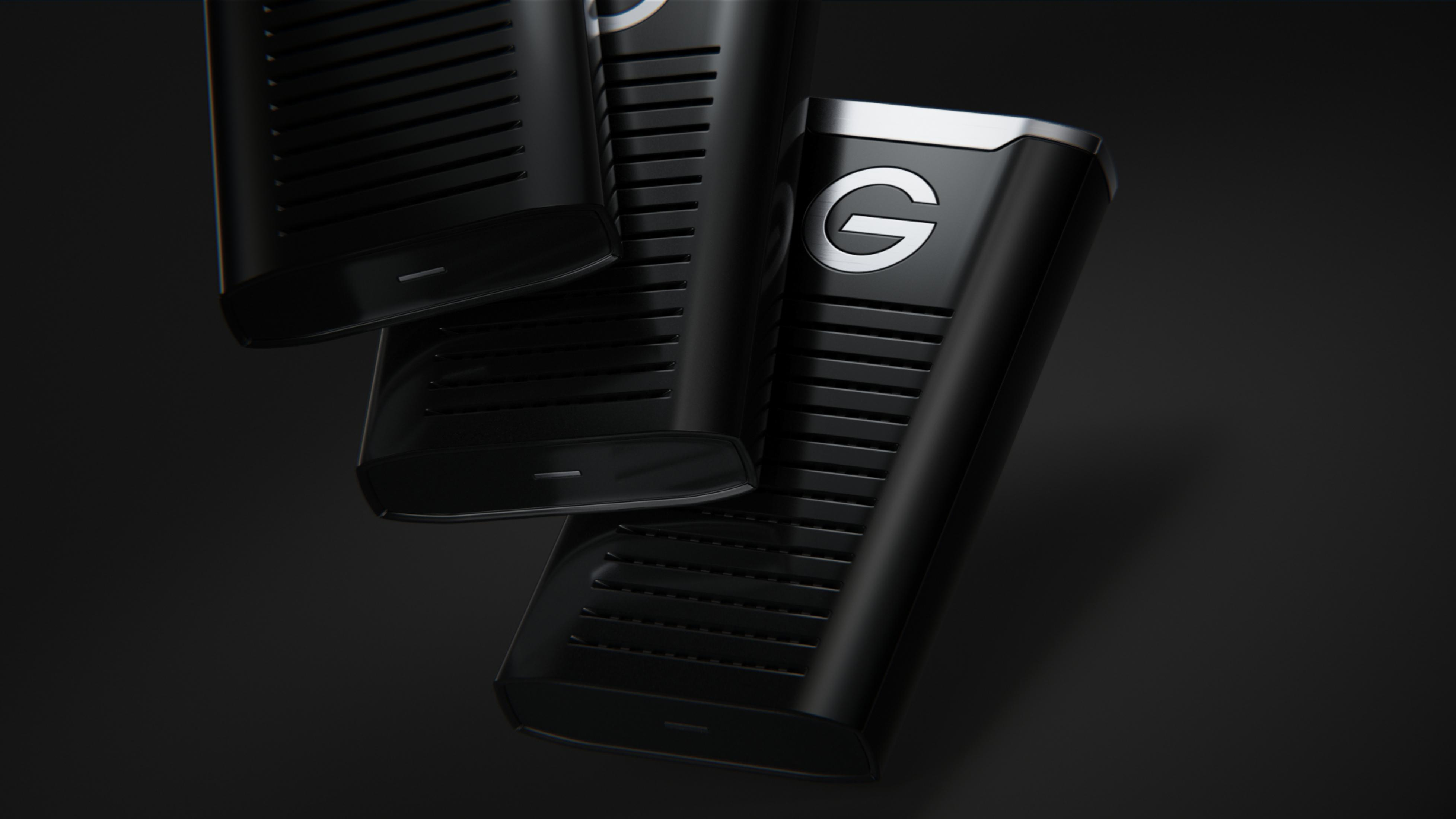 Trzy czarne zewnętrzne dyski twarde ułożone w stos, z ciemnym tłem.