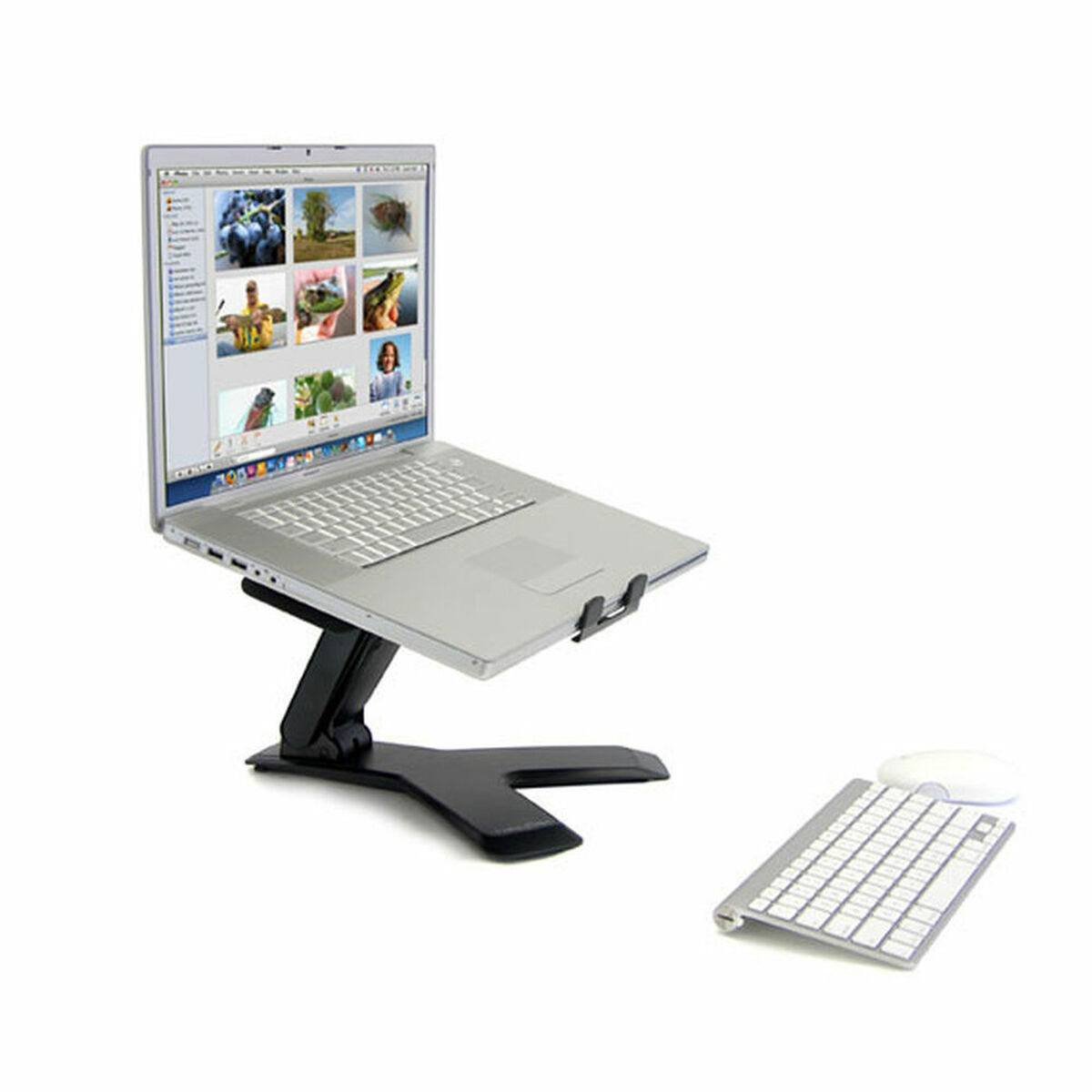 Ordinateur portable argenté sur support noir à côté d'un clavier et d'une souris.