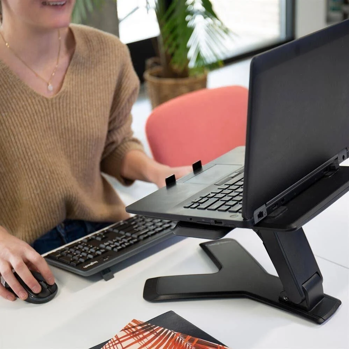 Une personne utilise un ordinateur portable sur un support avec clavier et souris.