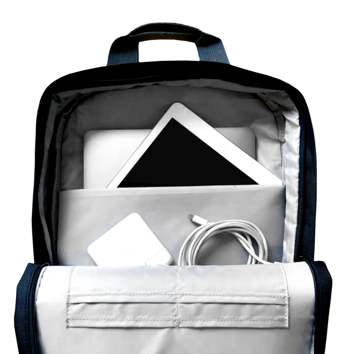 Mochila abierta con tableta, cargador y cable dentro, sobre fondo blanco.