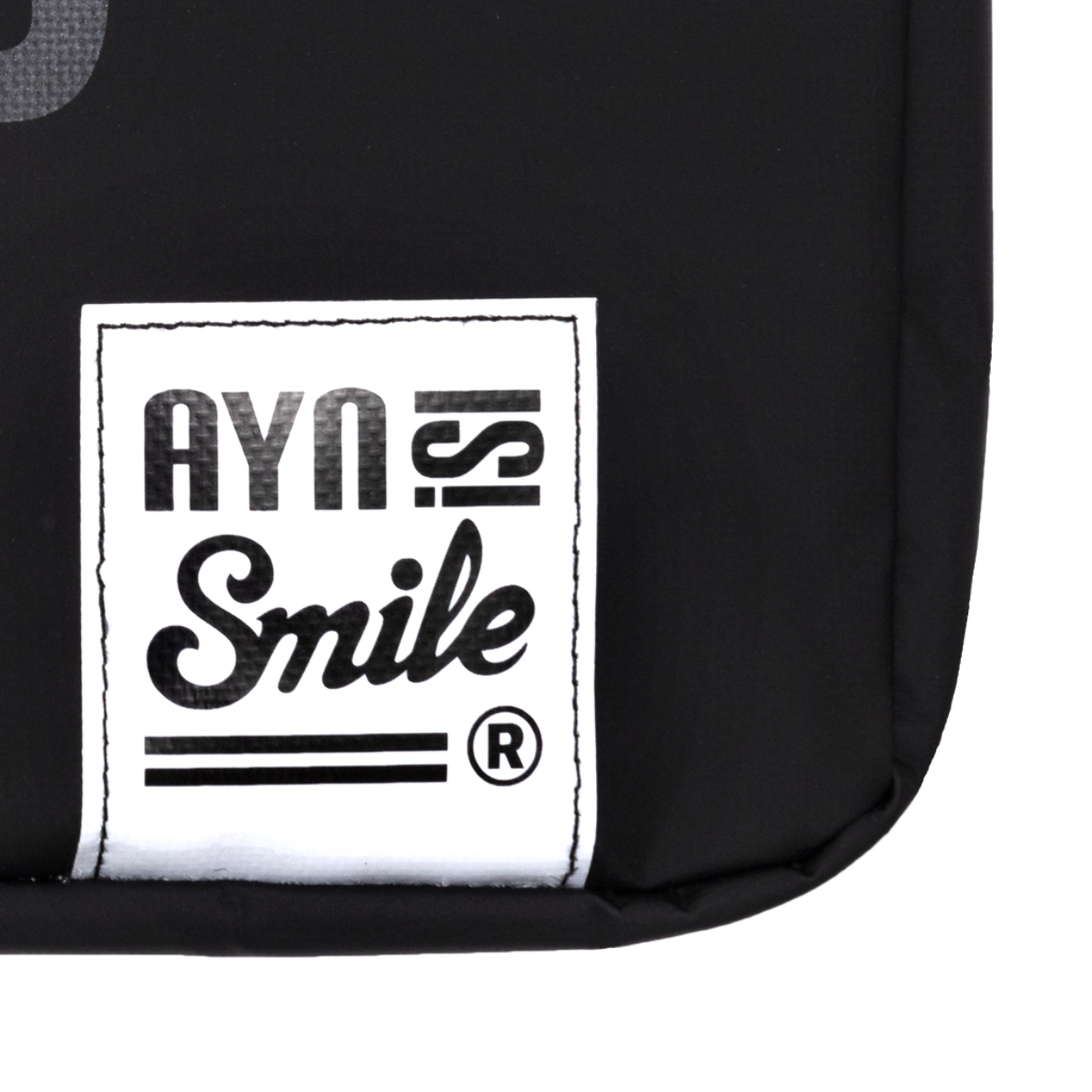 Primer plano de una bolsa negra con etiqueta blanca 'AYN Smile'.
