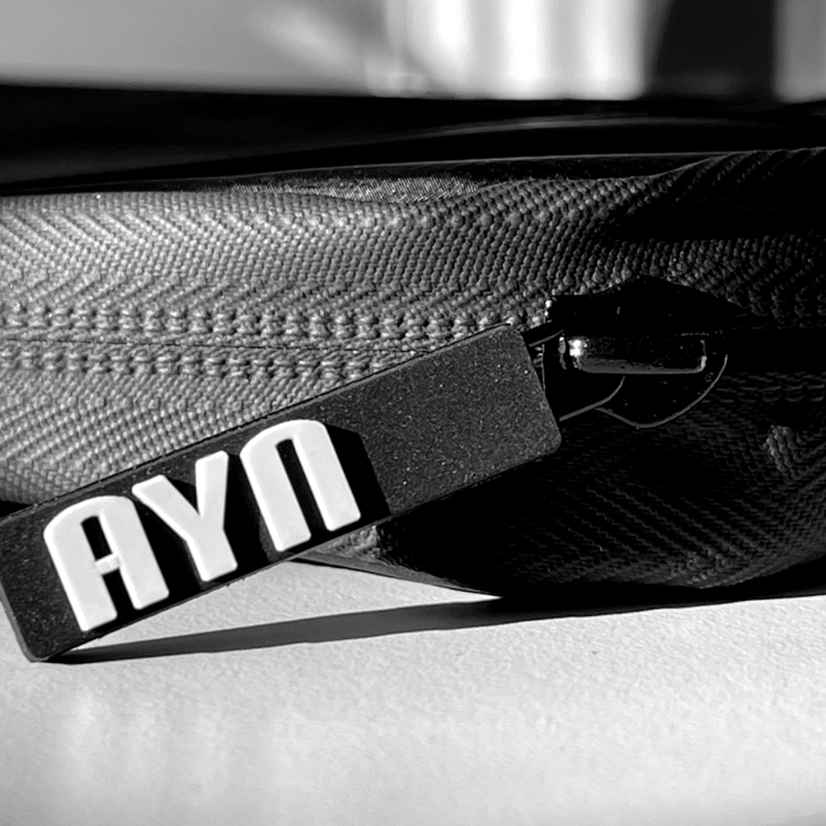 Un primer plano de una bolsa negra con cremallera y una etiqueta AYN.