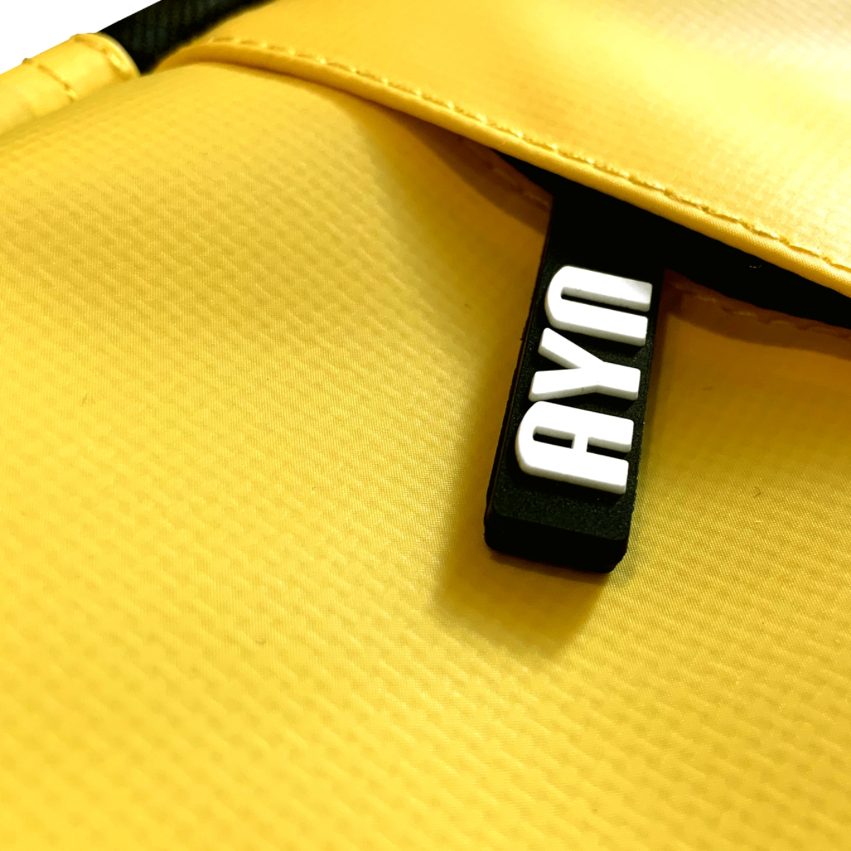 Bolsa amarilla con una etiqueta negra que dice 'AYO' en letras blancas.