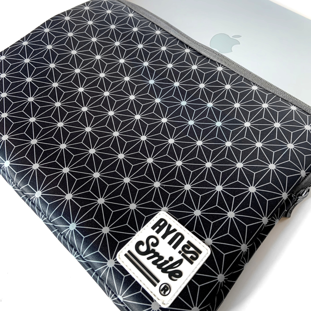 Una custodia per laptop nera con un motivo geometrico bianco e nero. Il marchio è visibile.