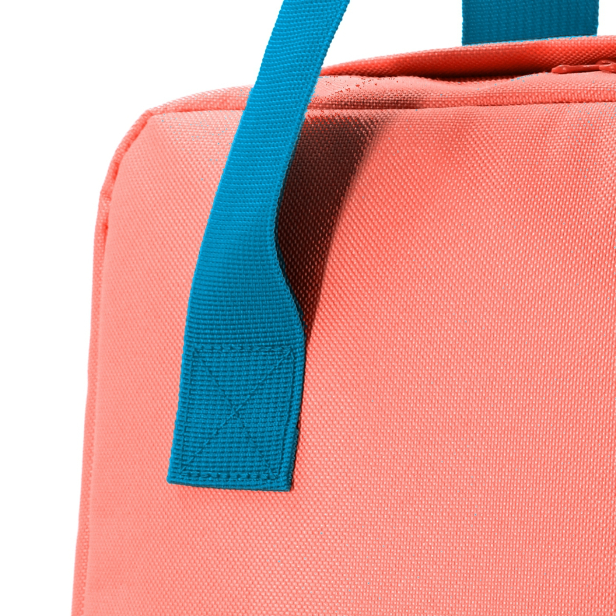 Bolso rosa coral con asa turquesa. El asa está cosida a la bolsa. Fondo blanco.