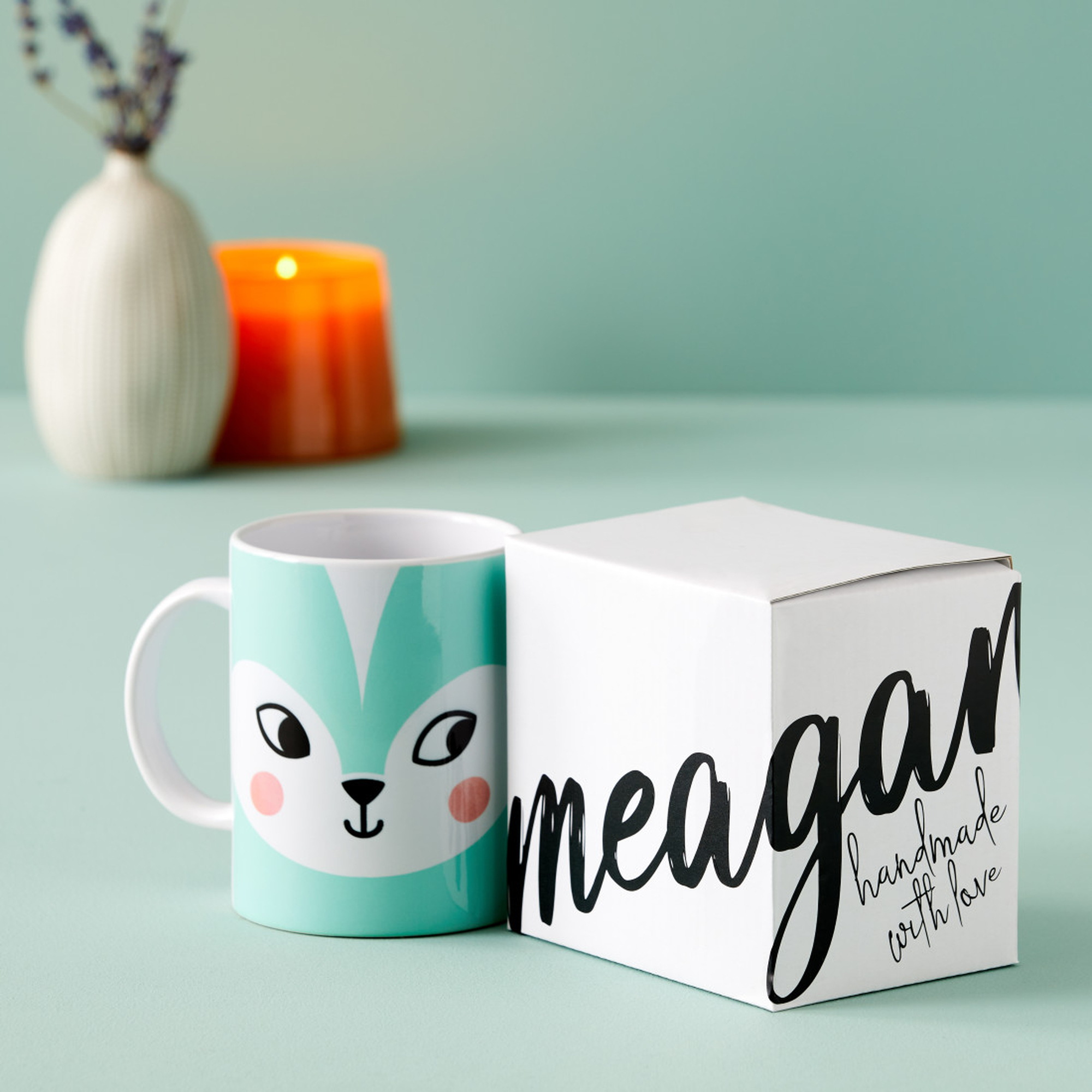 Una tazza con un design a volpe e una scatola bianca con la scritta 'meagan handmade with love'.
