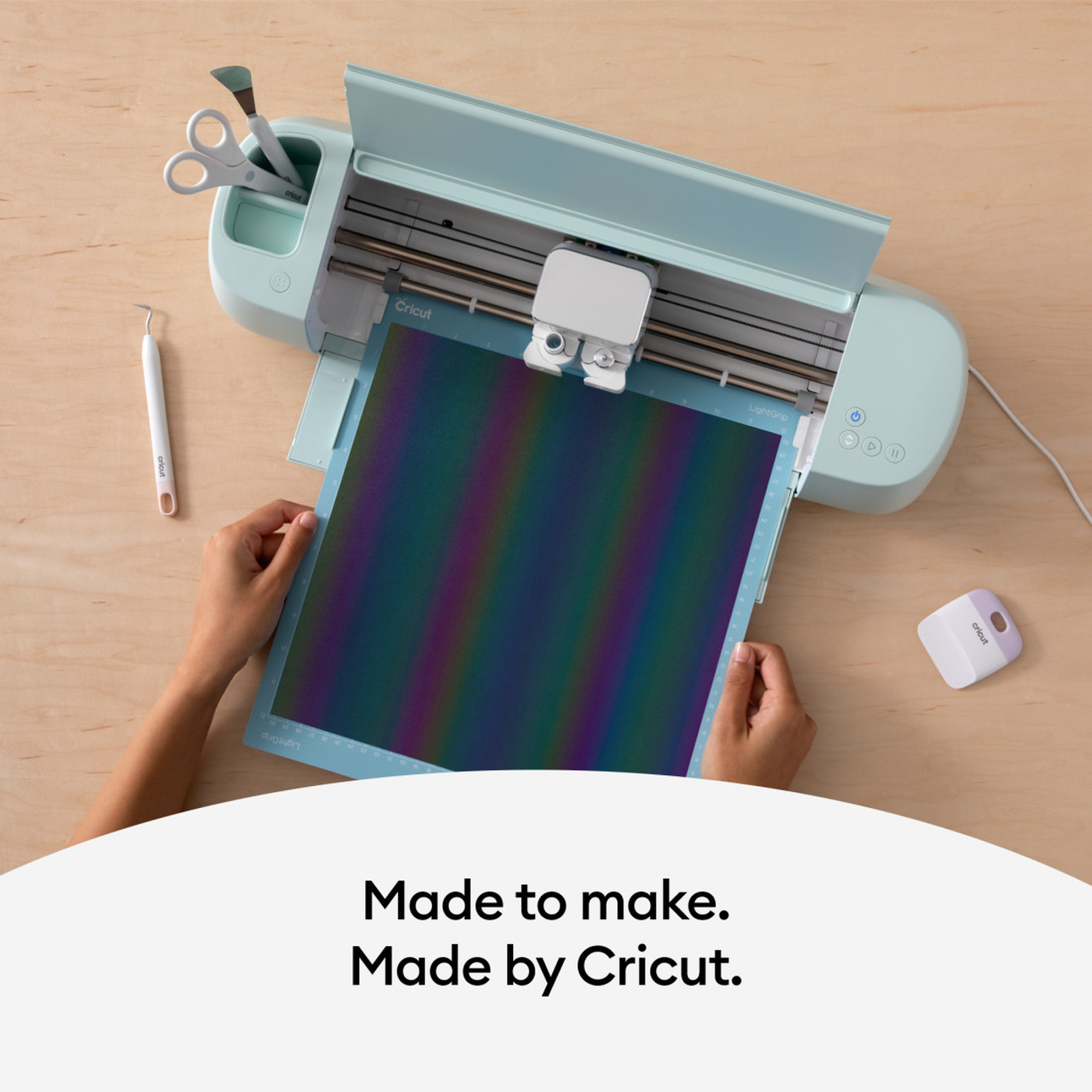 Eine Cricut-Schneidemaschine mit bunter Matte und Werkzeugen. Text: Made to make. Made by Cricut.