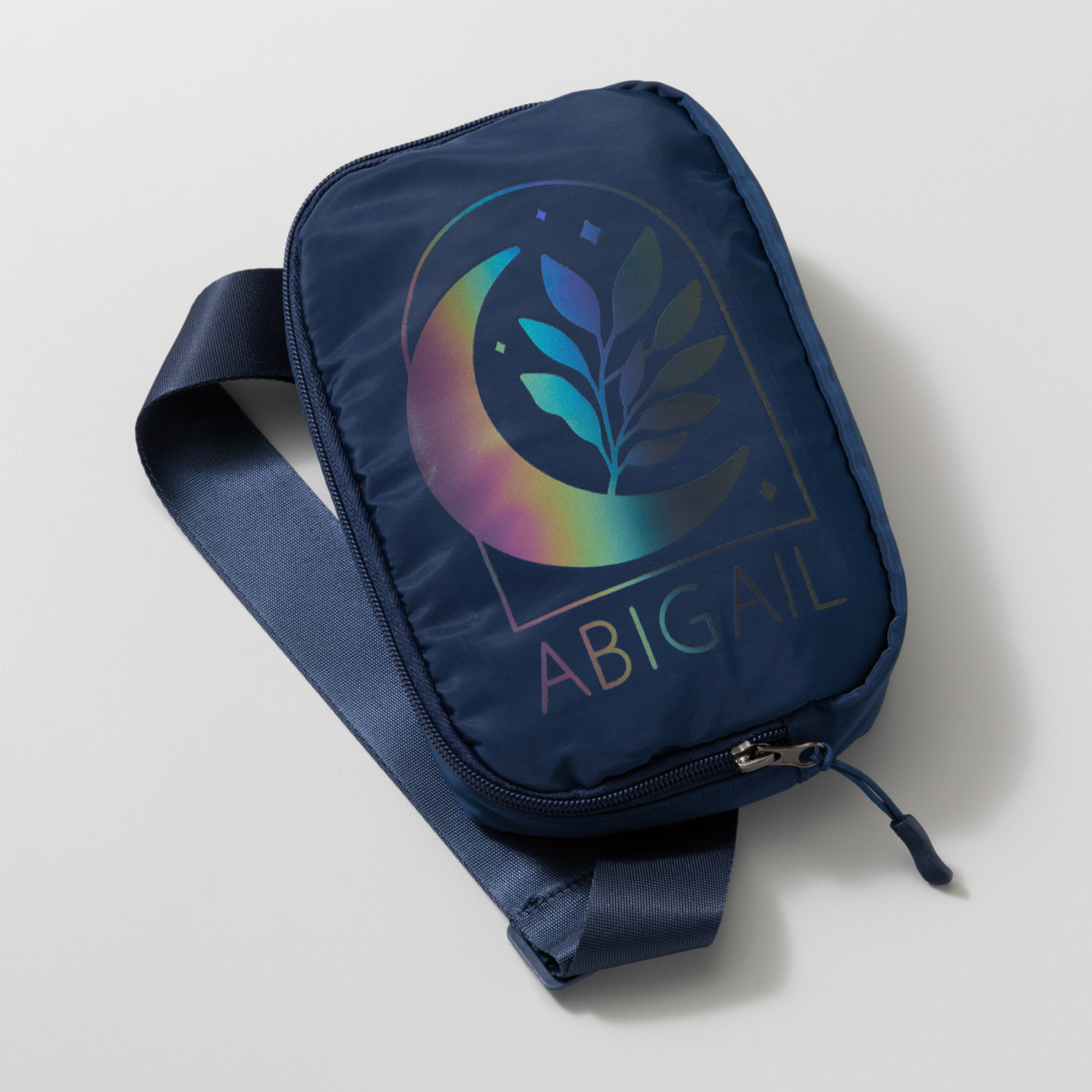 Eine marineblaue Tasche mit Schulterriemen. Sie hat ein Mond- und Blattdesign mit dem Namen 'ABIGAIL'.