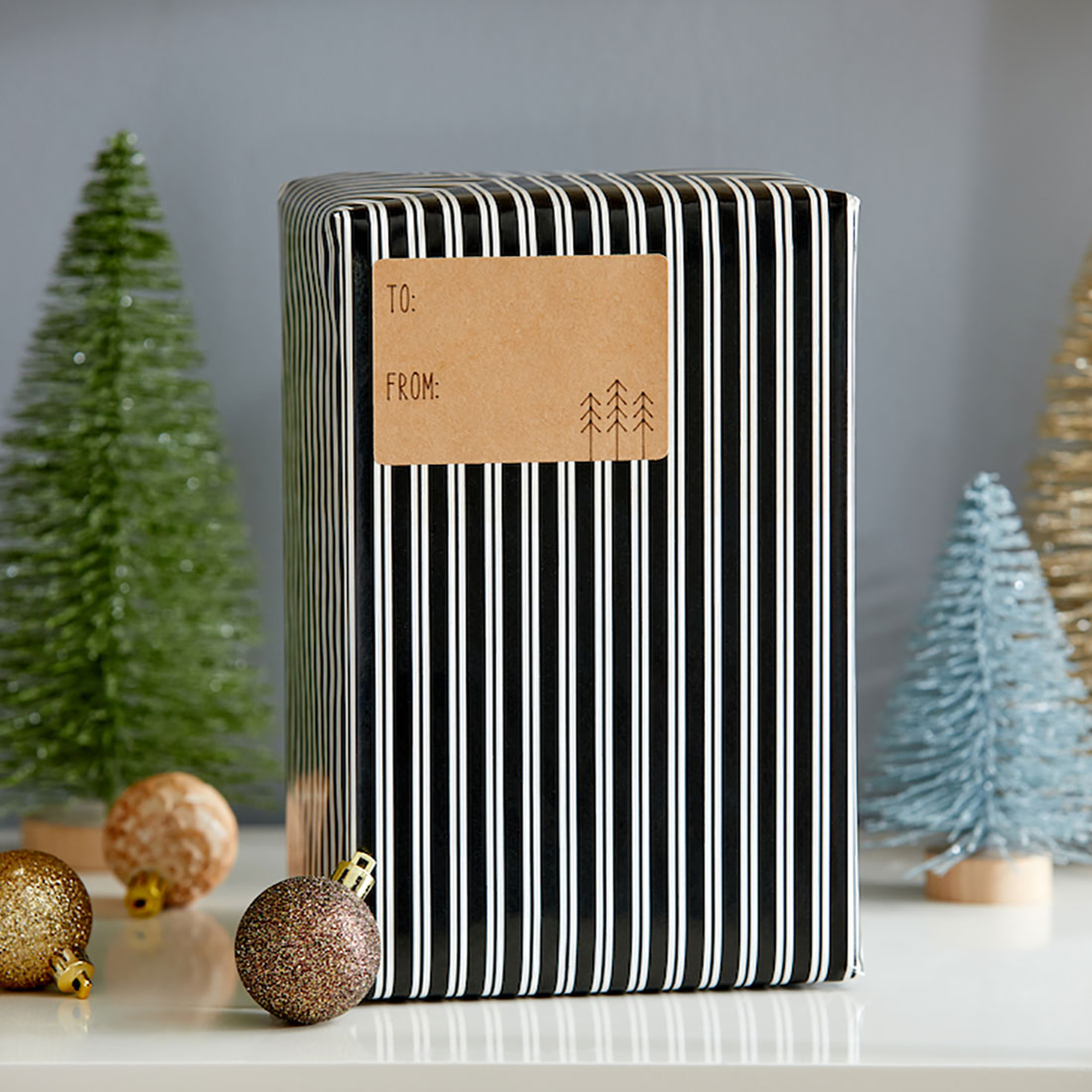 Ein verpacktes Geschenk mit Anhänger. Die Verpackung ist schwarz-weiß gestreift. Es gibt Weihnachtsschmuck.