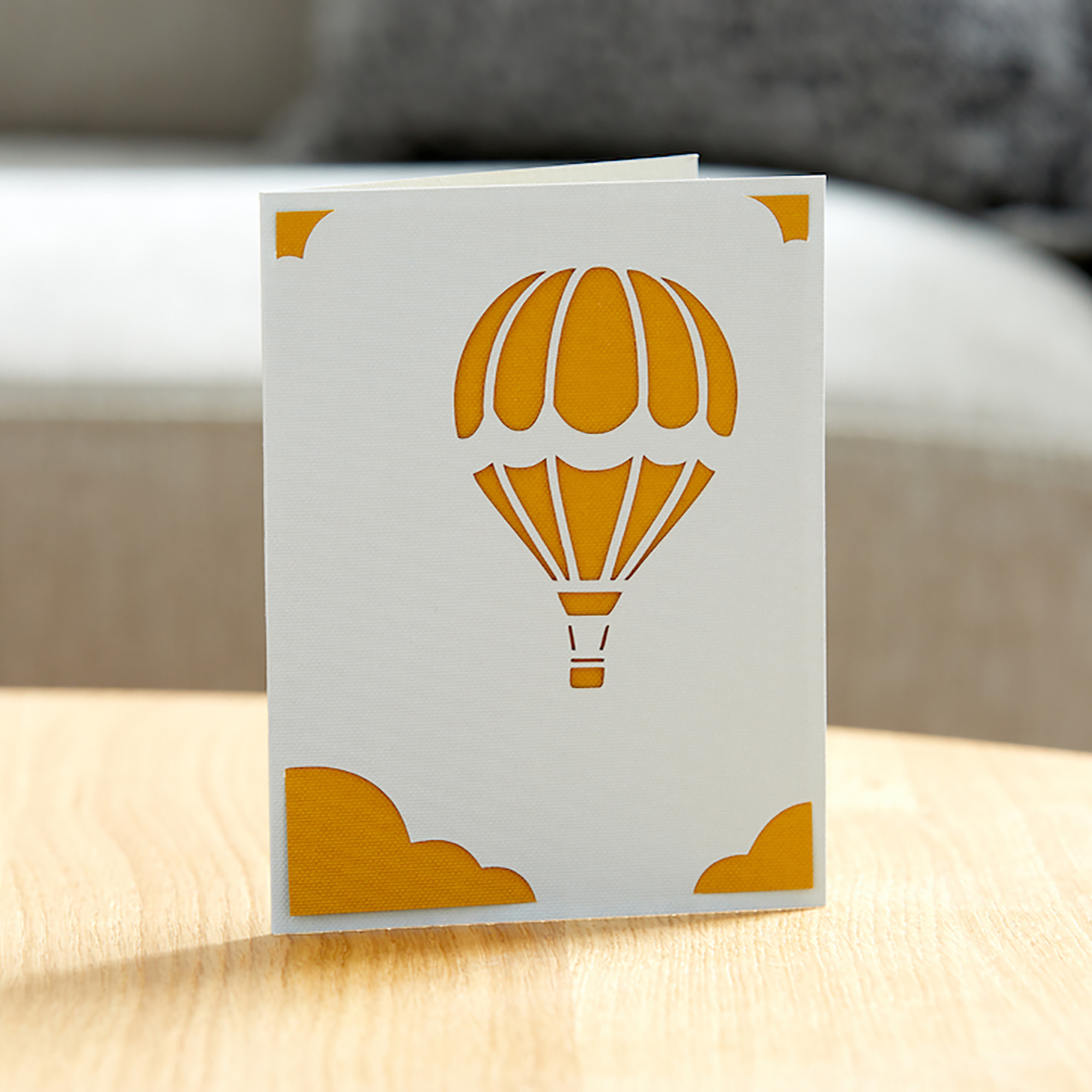 Grußkarte mit einem Heißluftballon-Design, ausgeschnitten, auf einem Holztisch.