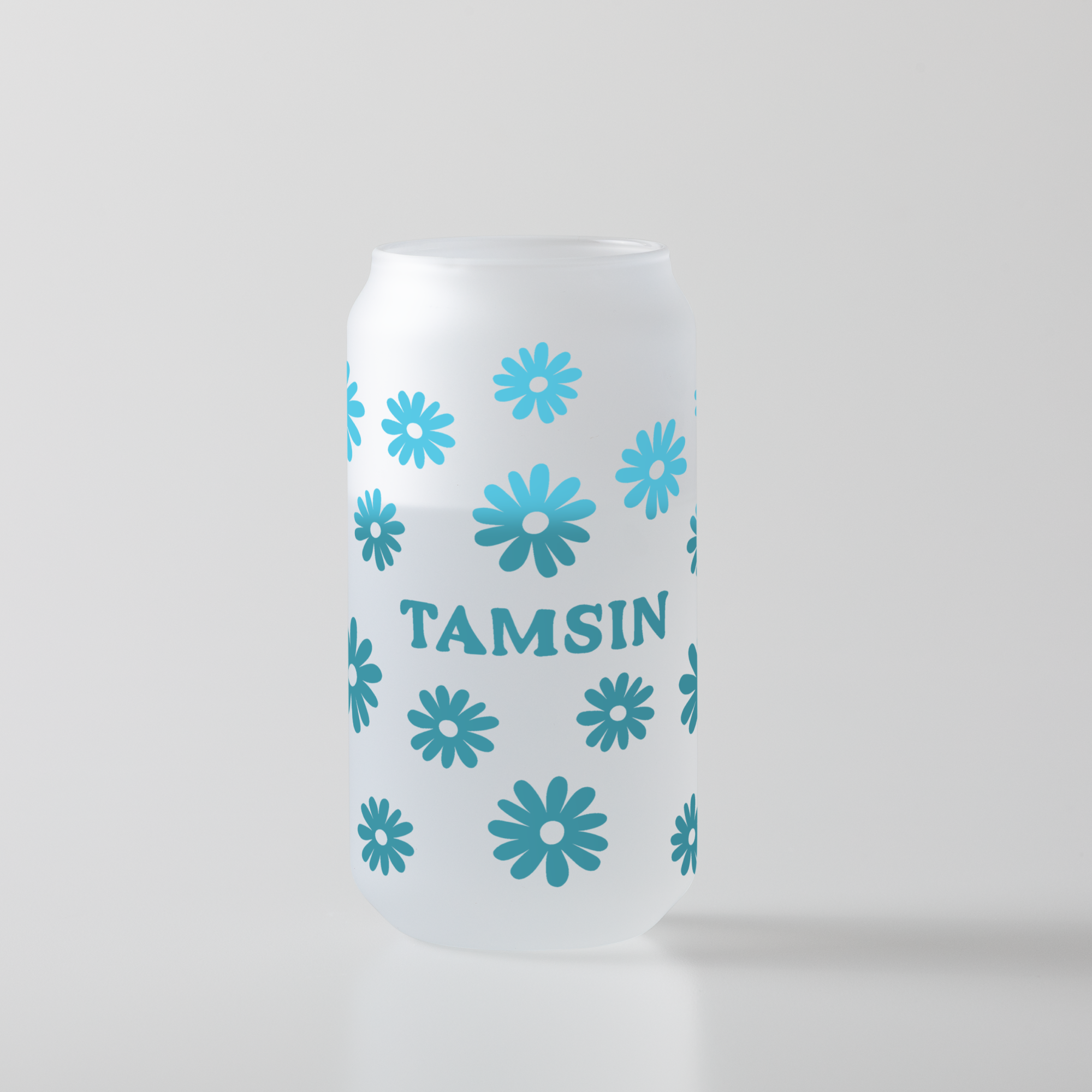 Weißes, dosenförmiges Glas mit dem Wort 'Tamsin' und blauen Blumendesigns.