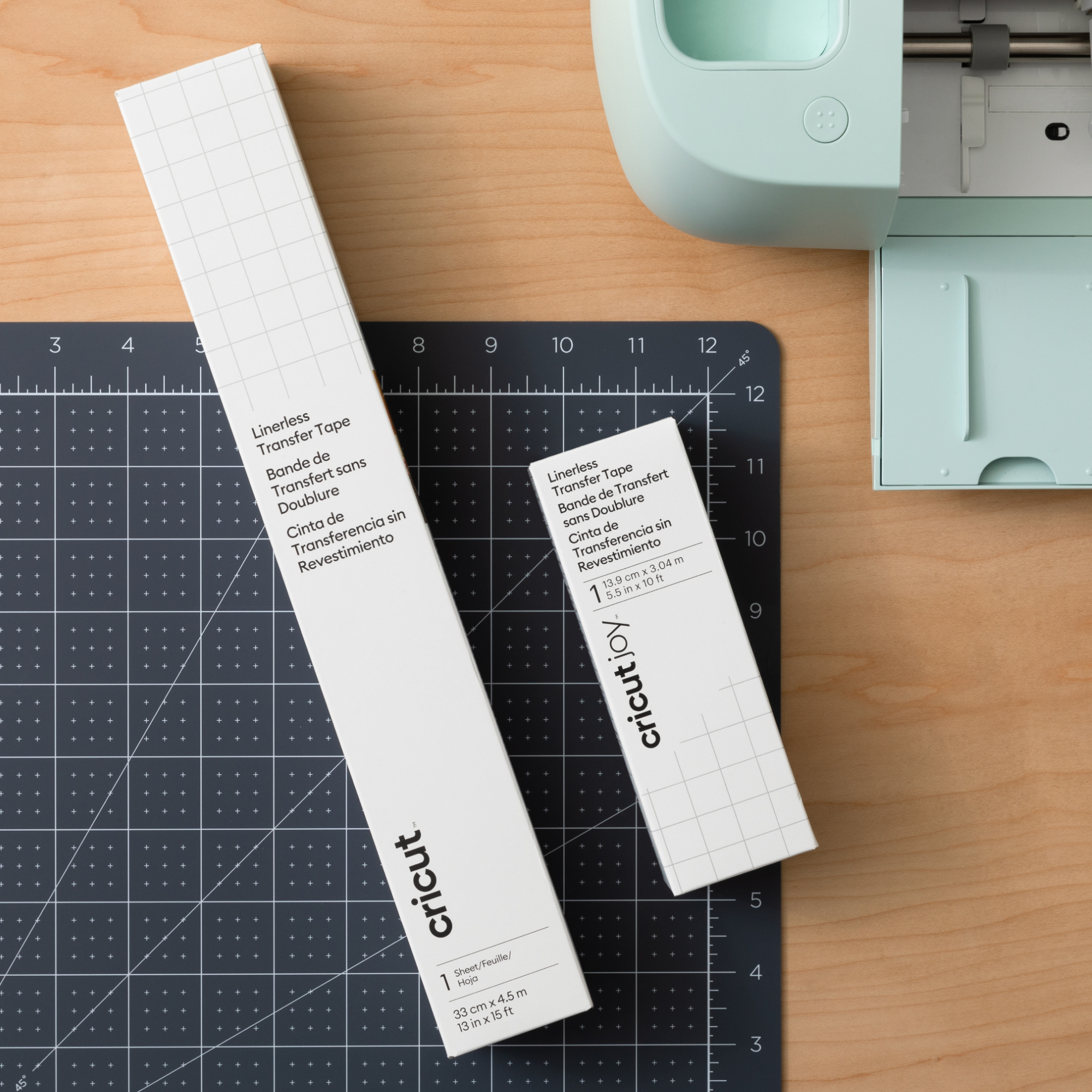 Zwei weiße Boxen mit Text und eine Schneidematte, neben einer Cricut-Maschine.