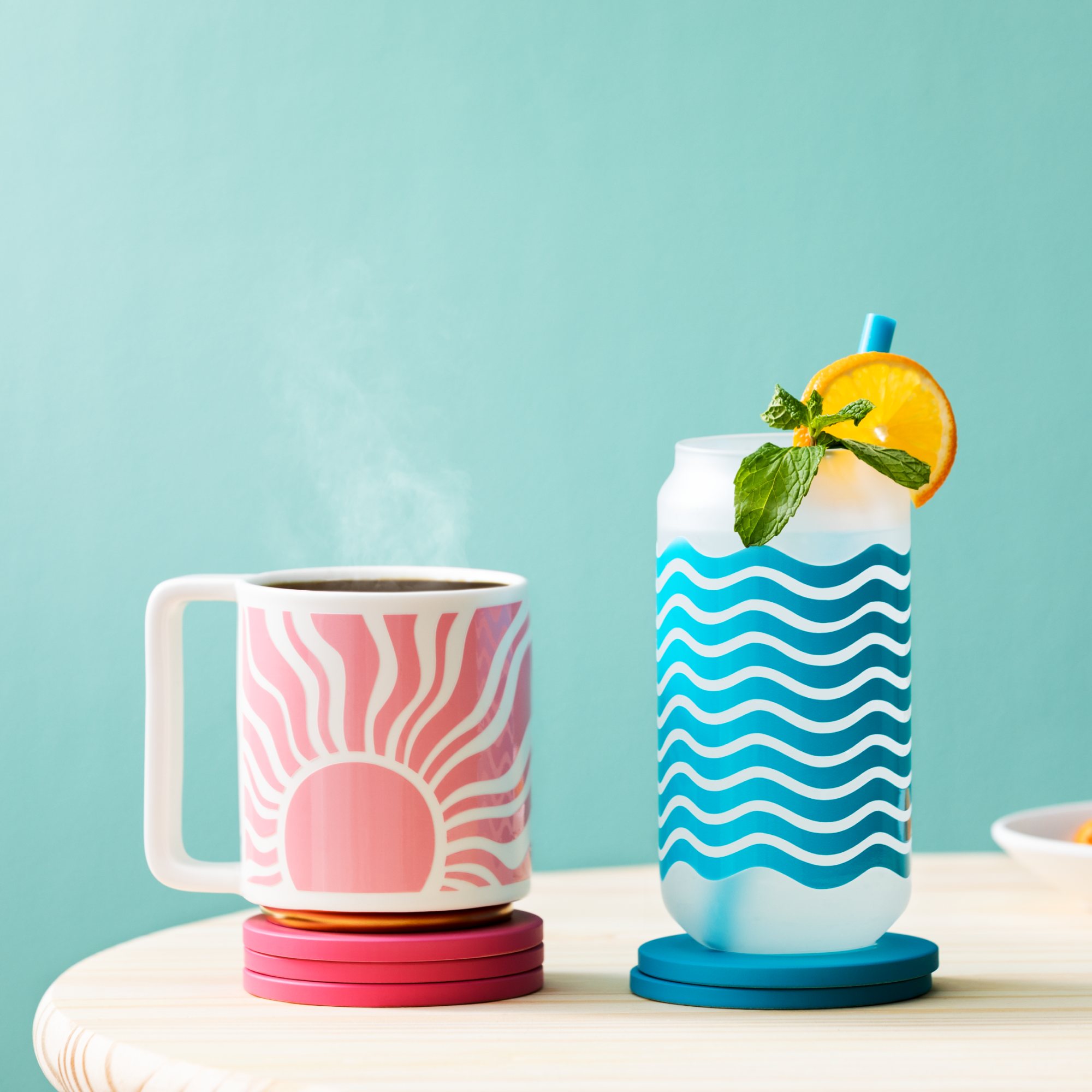 Eine Tasse mit Sonnendesign und ein Glas mit Cocktail auf einem Holztisch.