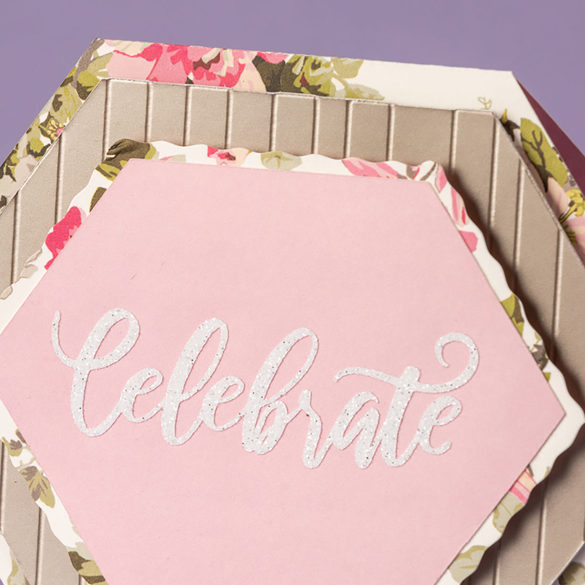 Rosa sechseckige Karten mit floralen Rändern und dem Wort 'Celebrate'. Lila Hintergrund.