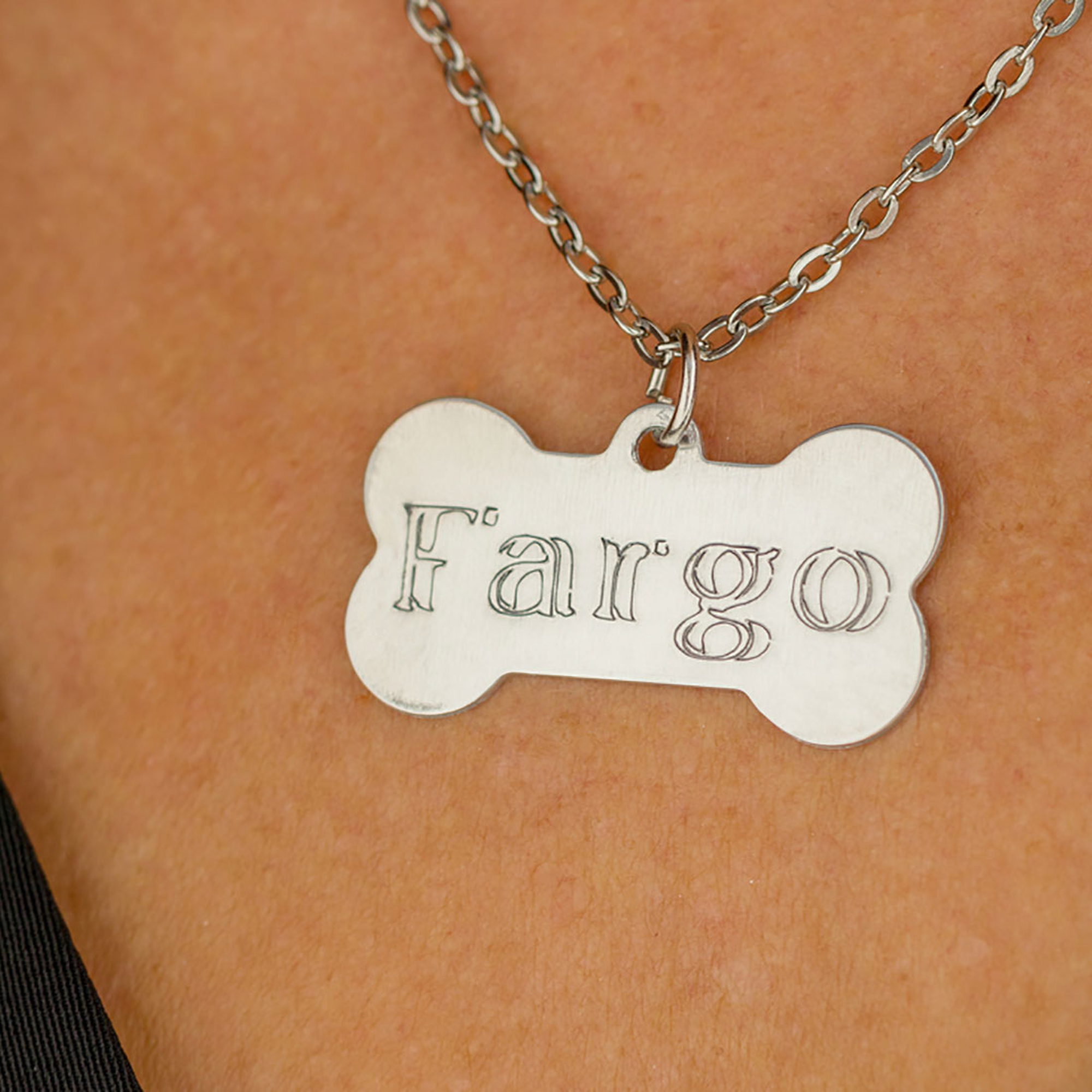 Ein Hundehalsband mit dem eingravierten Namen 'Fargo', das an einer Halskette hängt.