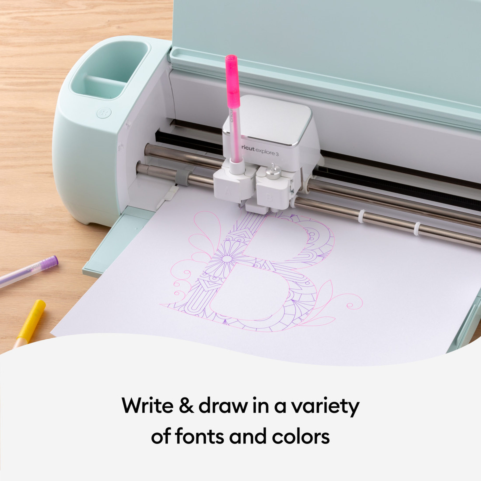 Eine Cricut-Maschine mit einem rosa Stift zeichnet ein Design auf Papier, Text unten.