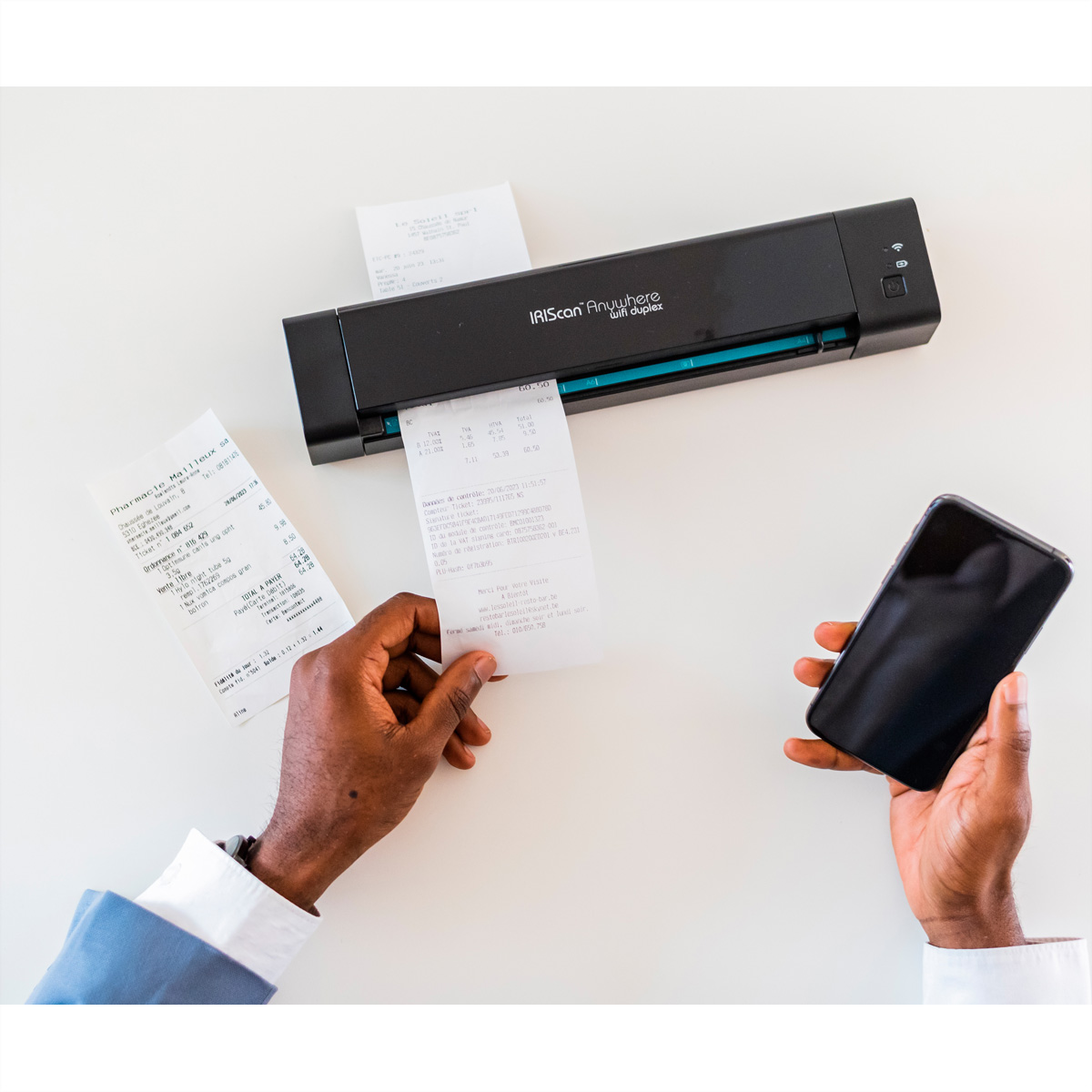 Een persoon scant bonnen met een zwarte scanner. Een telefoon in de andere hand.
