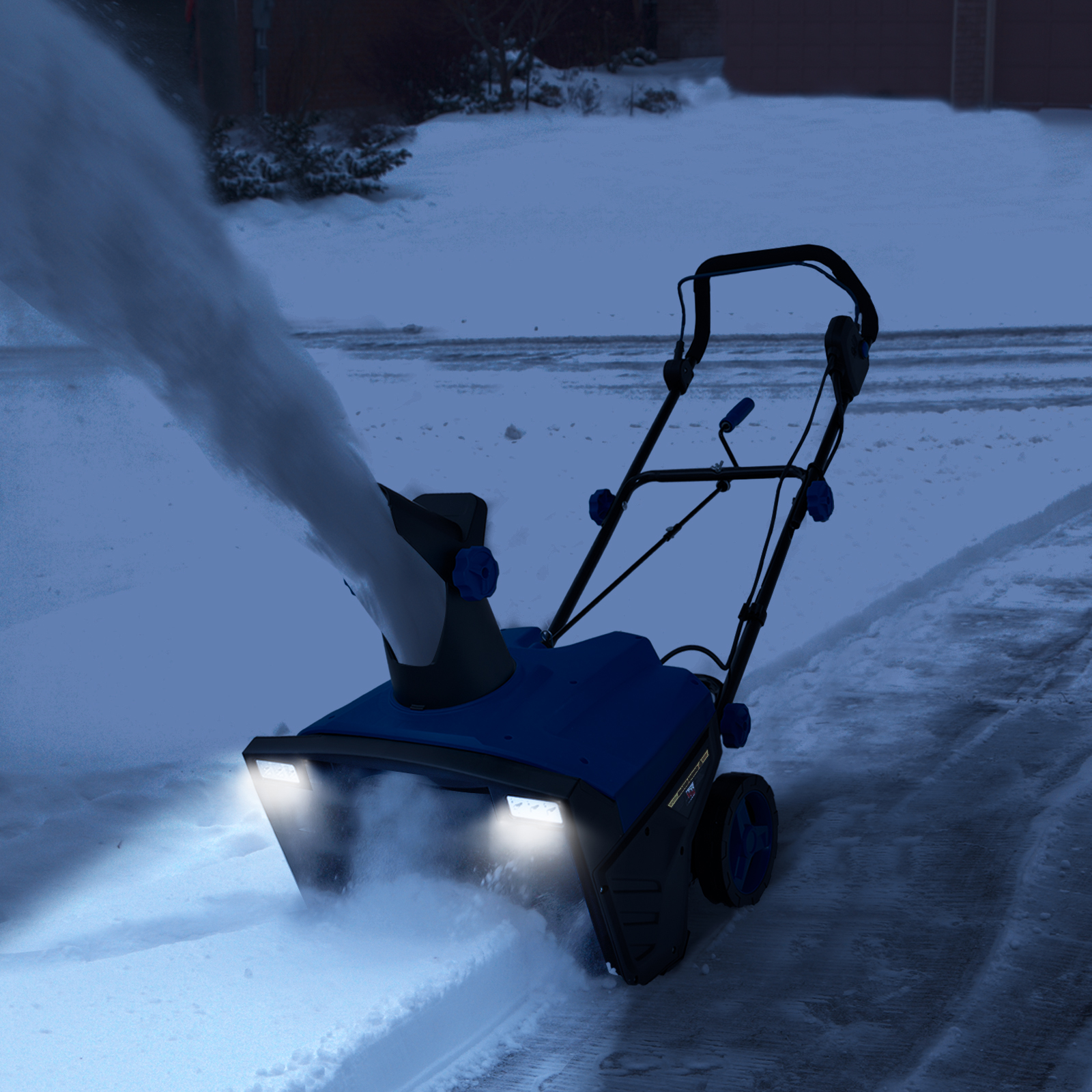 Eine blaue Schneefräse in Aktion, die nachts Schnee räumt. Die Lichter sind an und Schnee wird ausgeblasen.