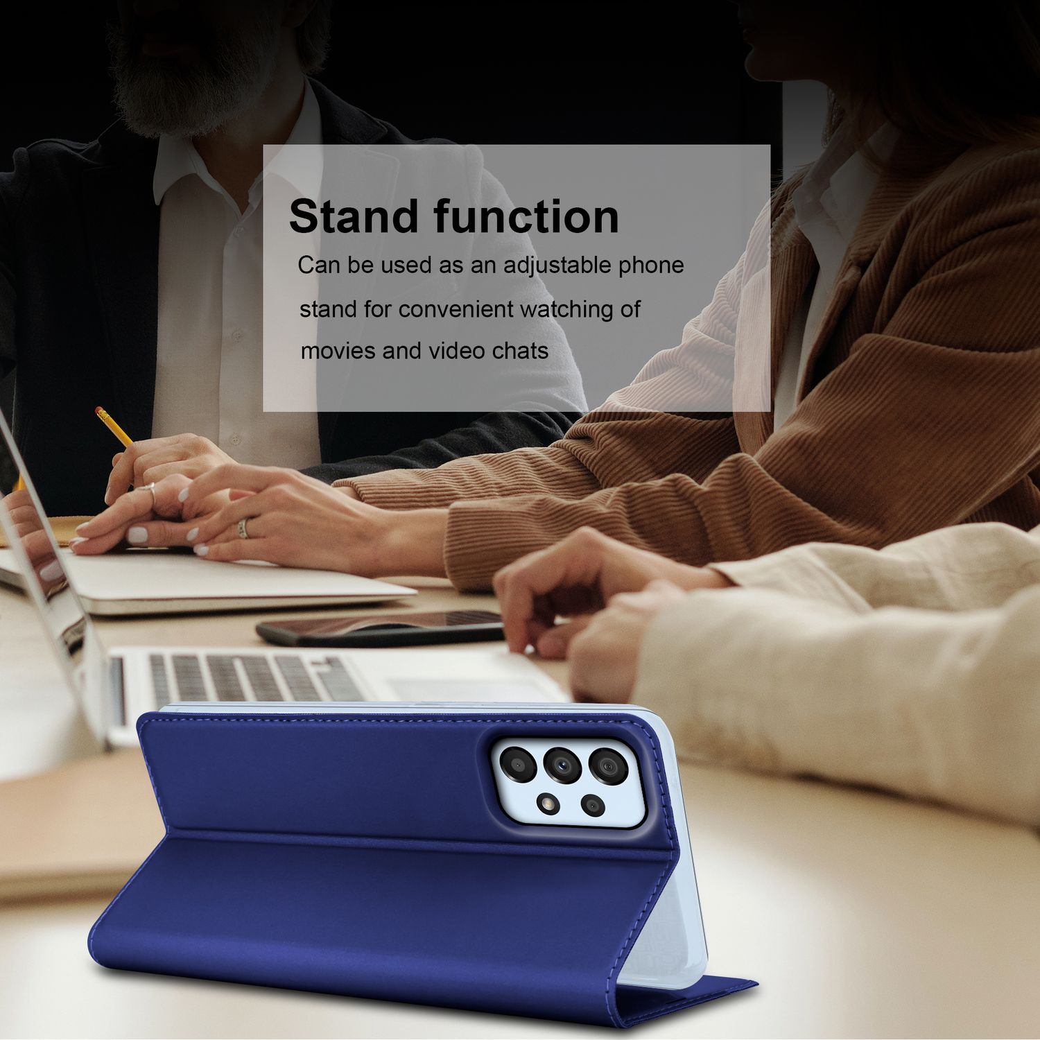 Telefon in einer blauen Hülle, auf einem Tisch aufgestellt. Personen und Laptops im Hintergrund unscharf.